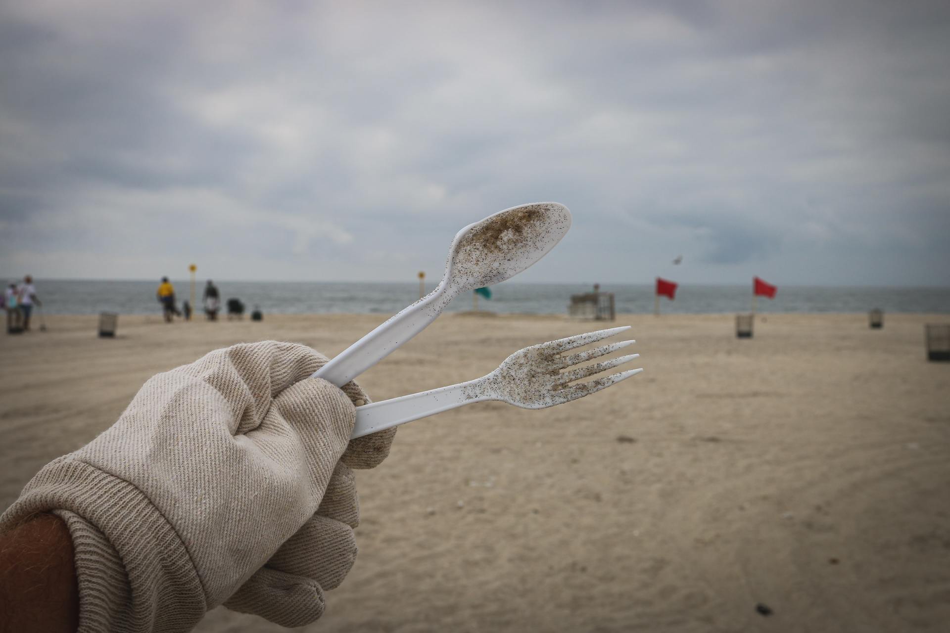 A person is holding a toothbrush and fork on the beach.