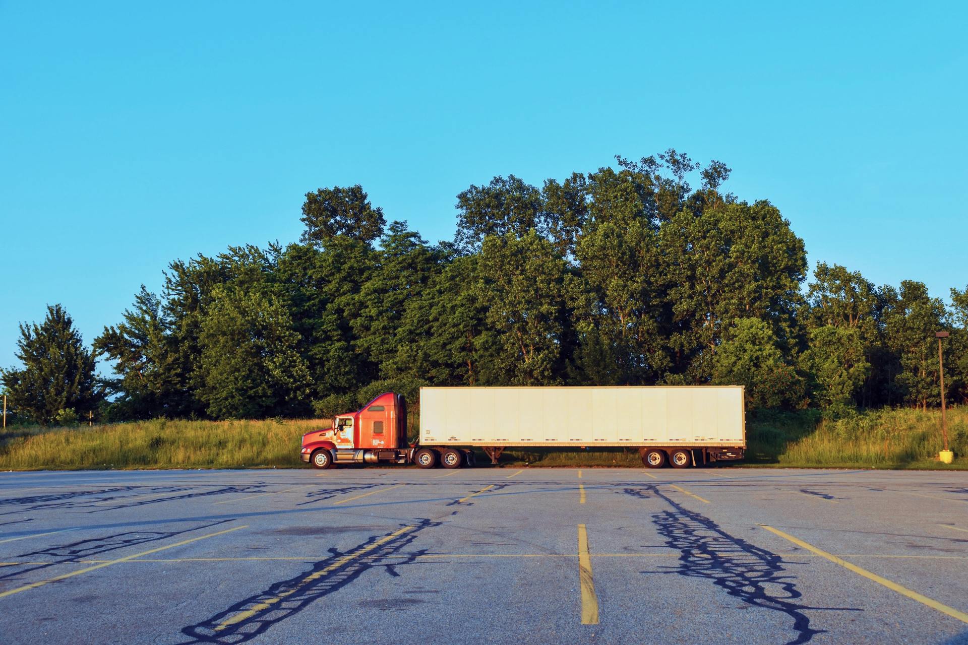 A red semi truck is parked in a parking lot.