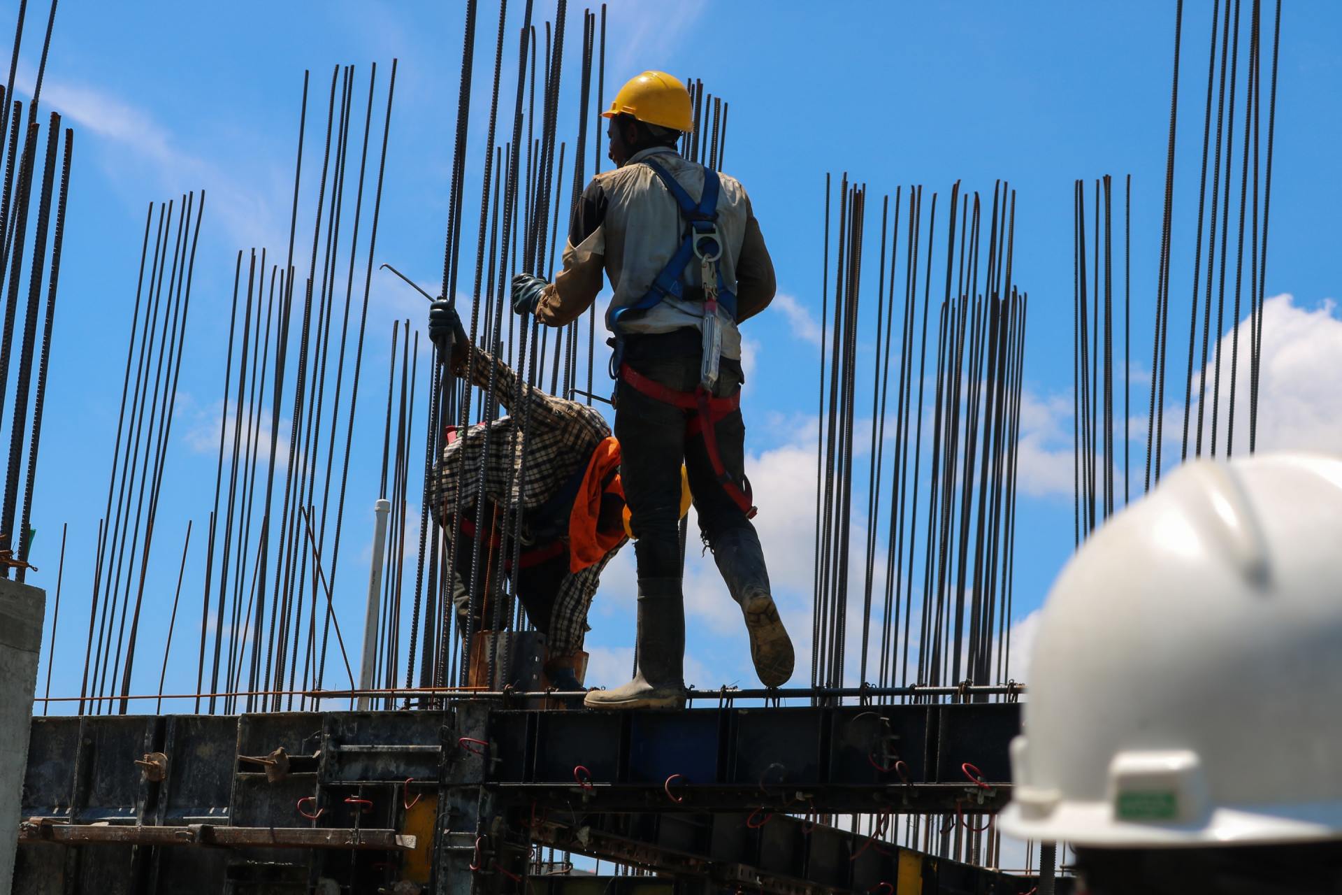 Builders in helmets erecting metal rods