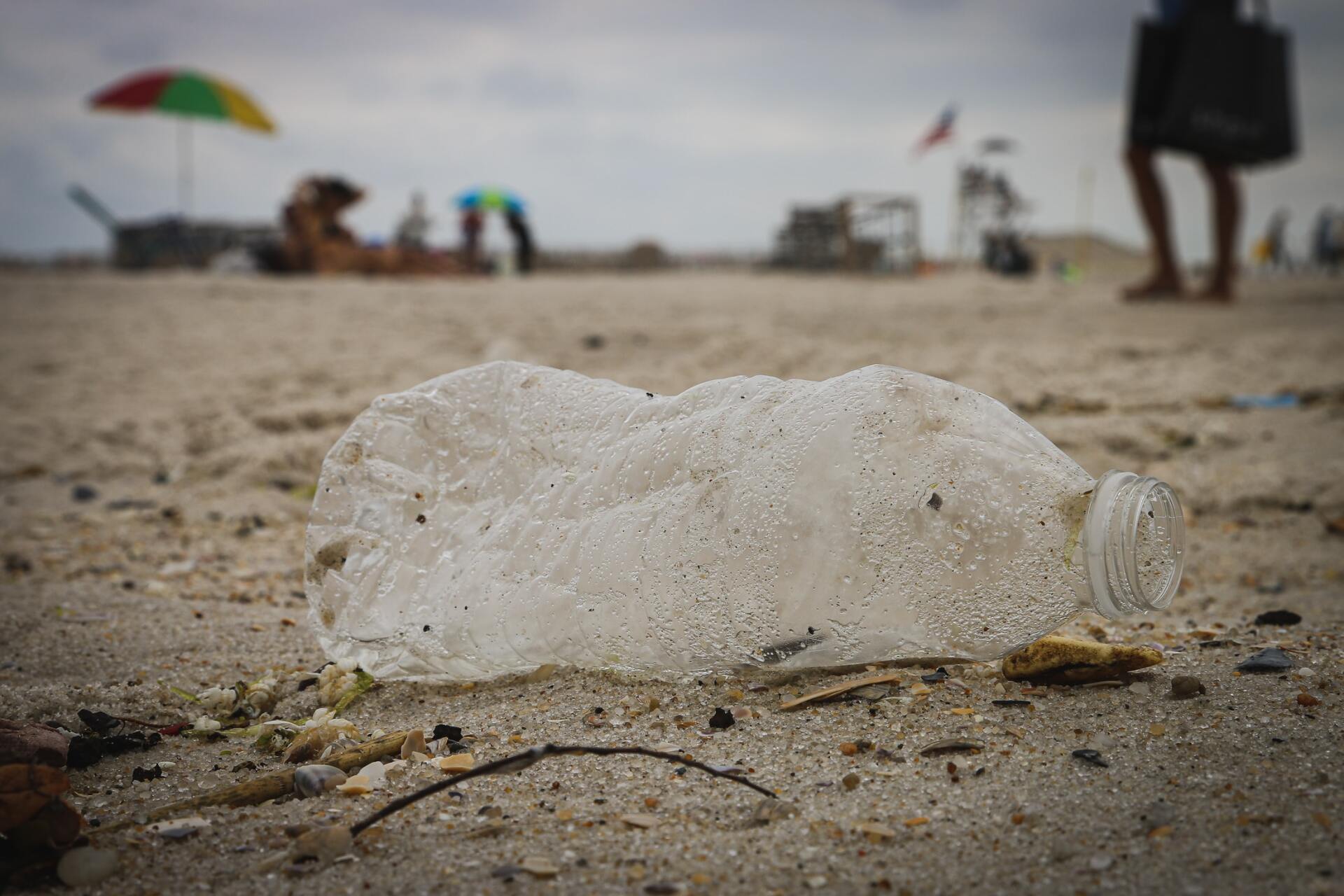 A plastic bottle is laying on the sand on a beach.