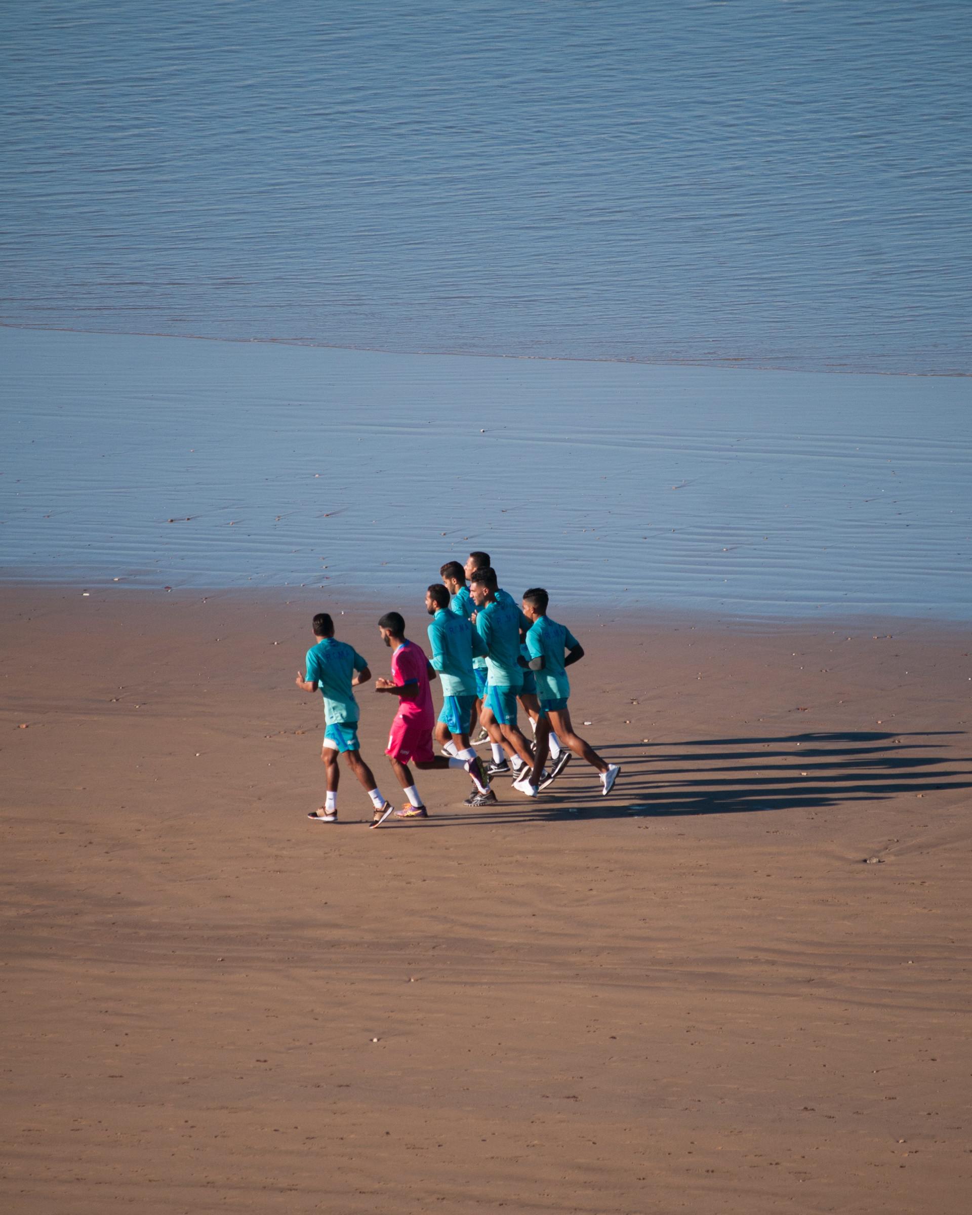Un groupe de personnes court sur la plage près de l'eau