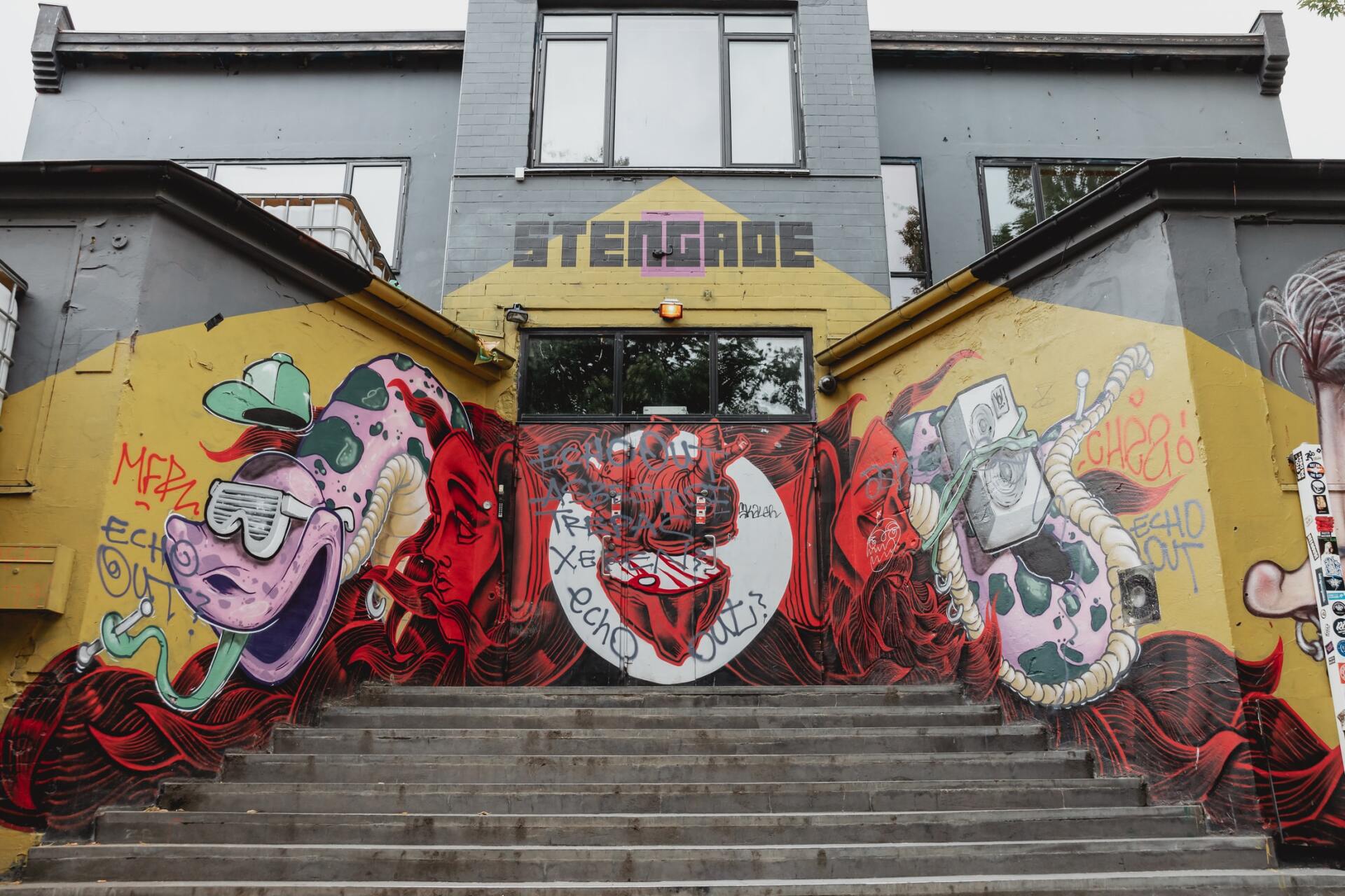 A building with graffiti on the side of it and stairs leading up to it.