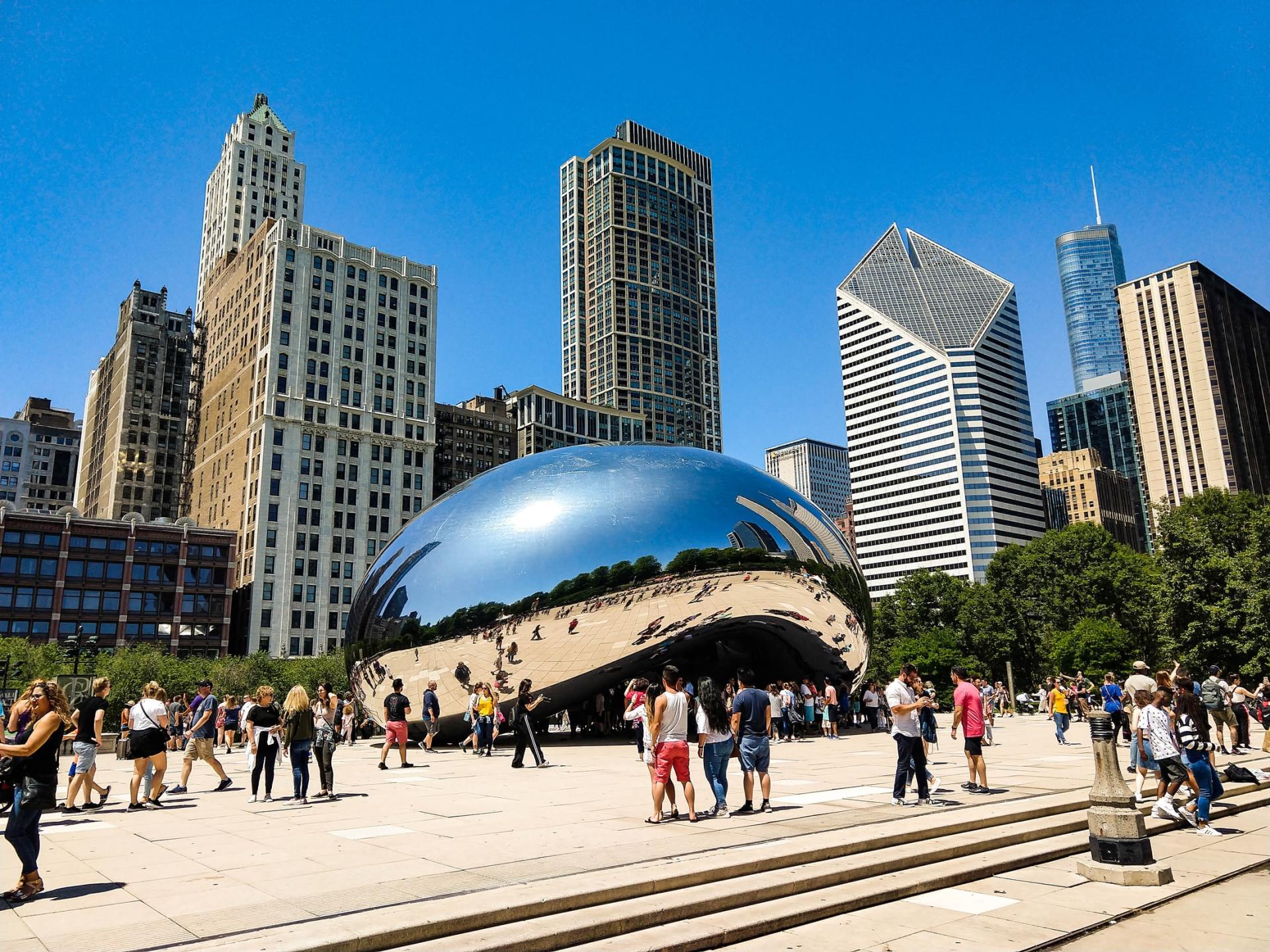 A group of people are standing in front of a large sculpture in a city park.