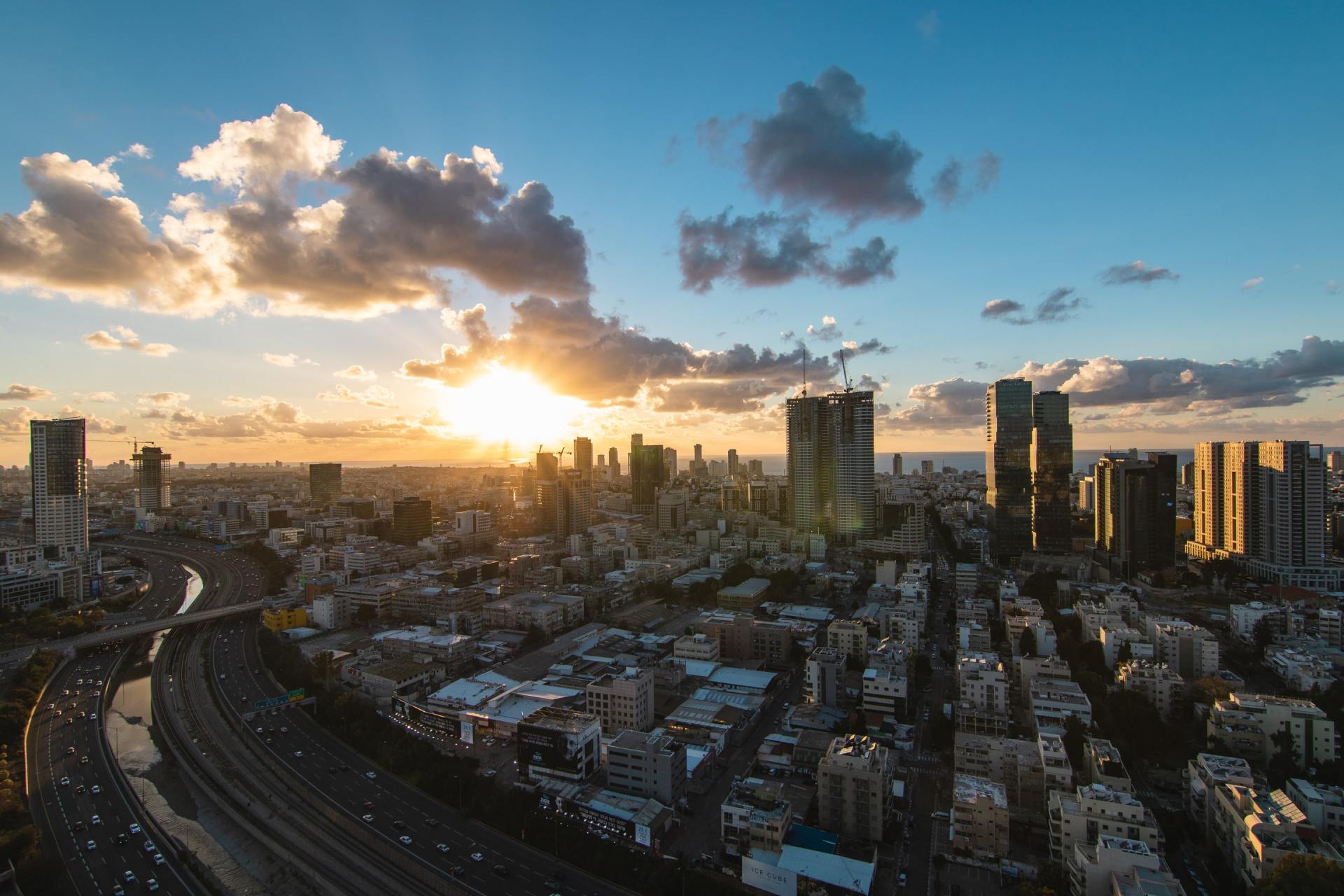 מבט אווירי של עיר בשקיעה עם נהר בחזית.