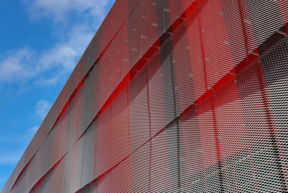 Close up of side of modern building with layers of red metal panels in waves