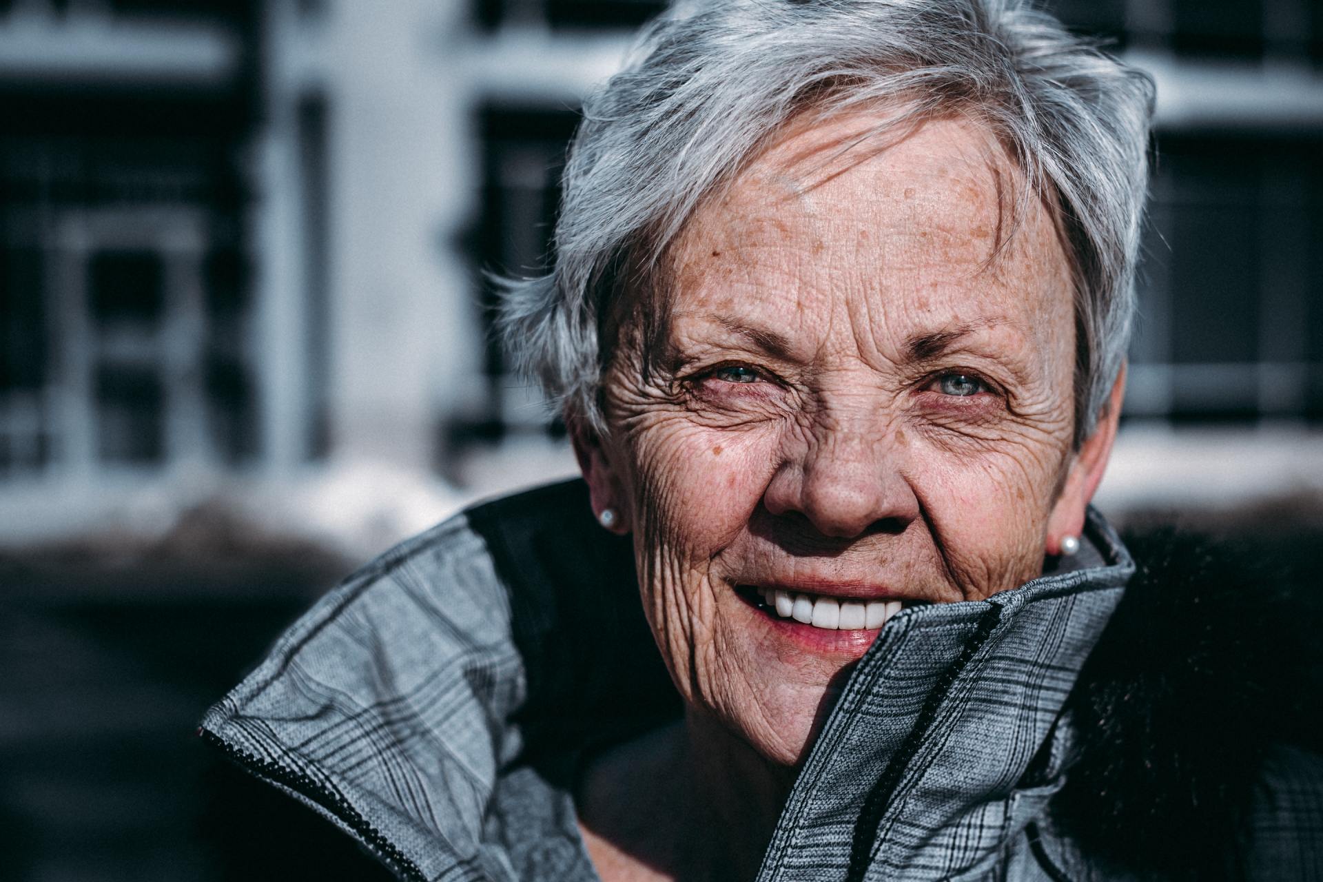 An elderly woman with gray hair is smiling for the camera.