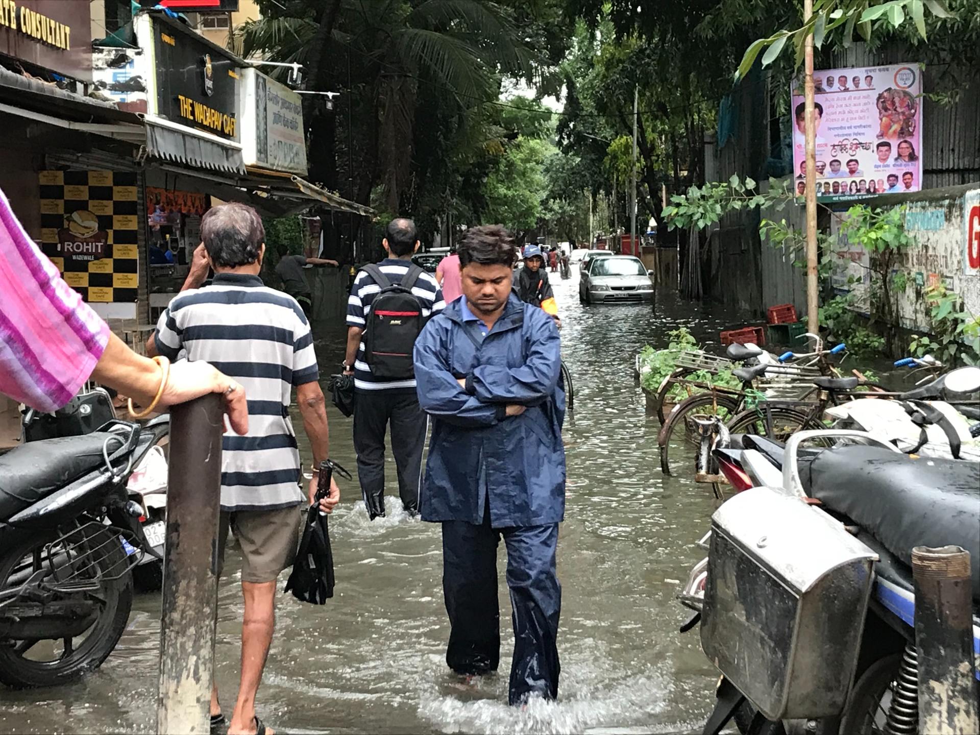 A group of people are walking down a flooded street.