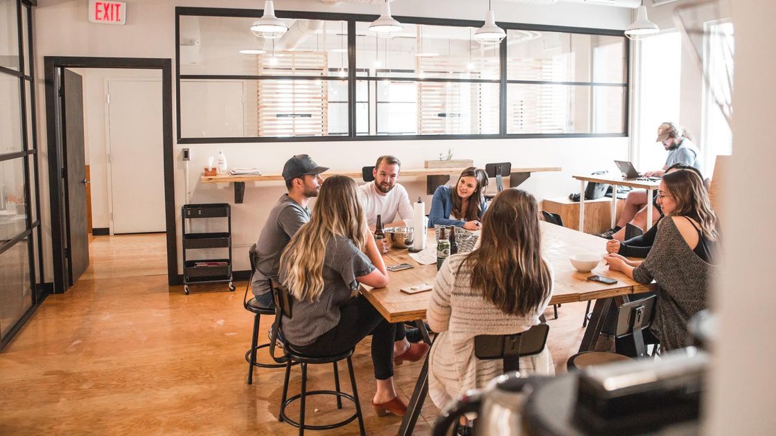 A group of people are sitting around a table in an office having a meeting.