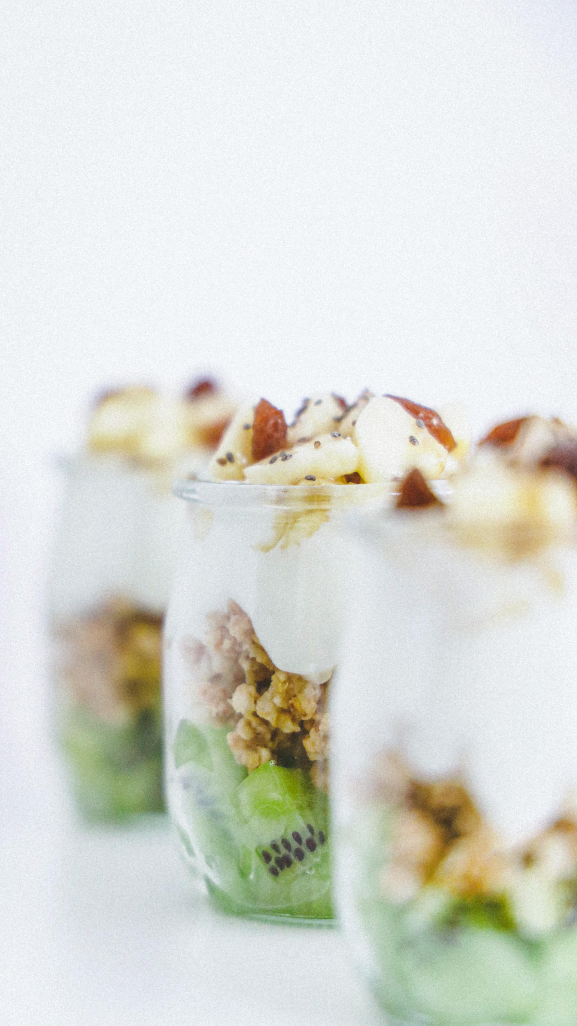 Een close up van een dessert in een glas met kiwi en yoghurt.