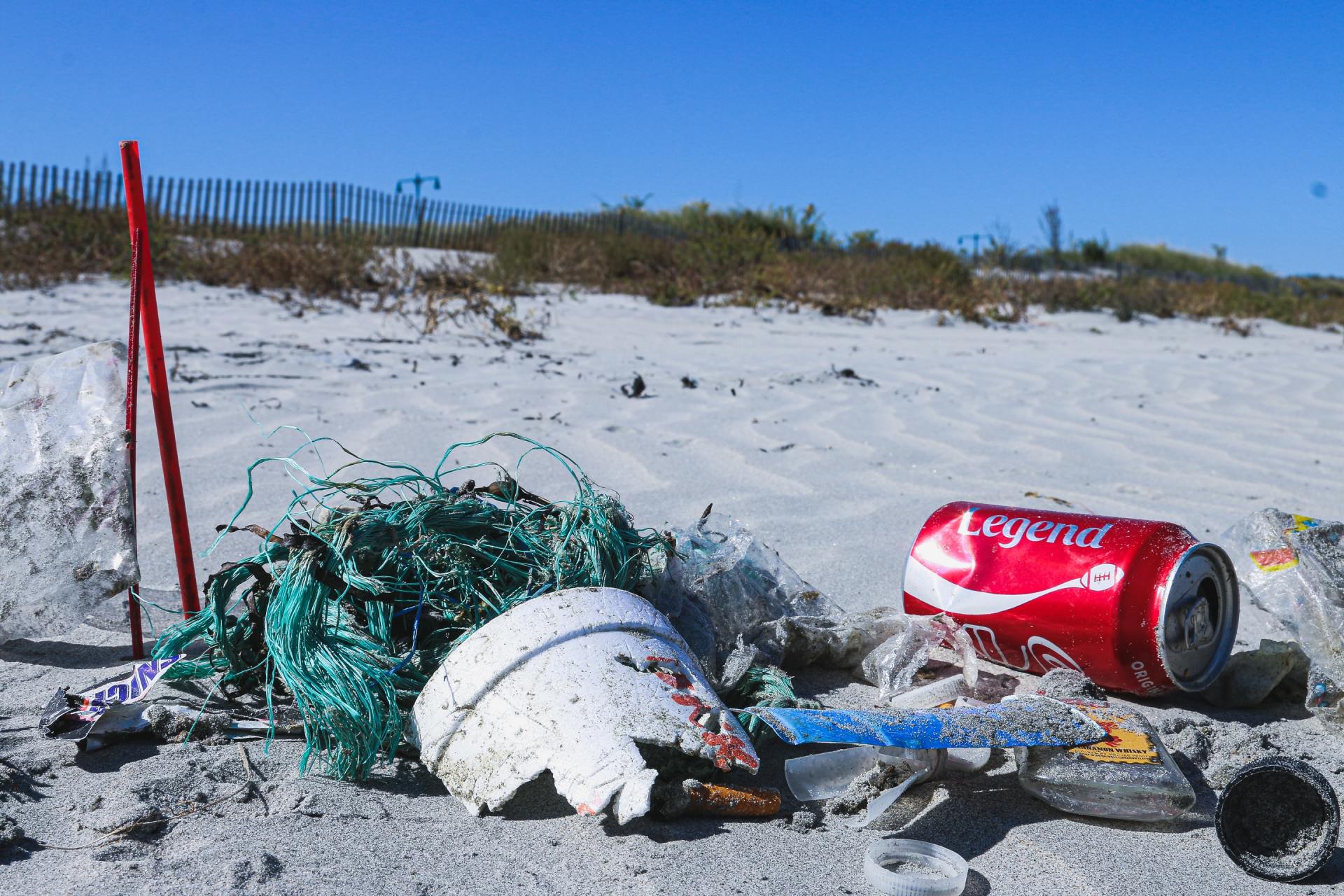 A coca cola can is laying on the sand on a beach.