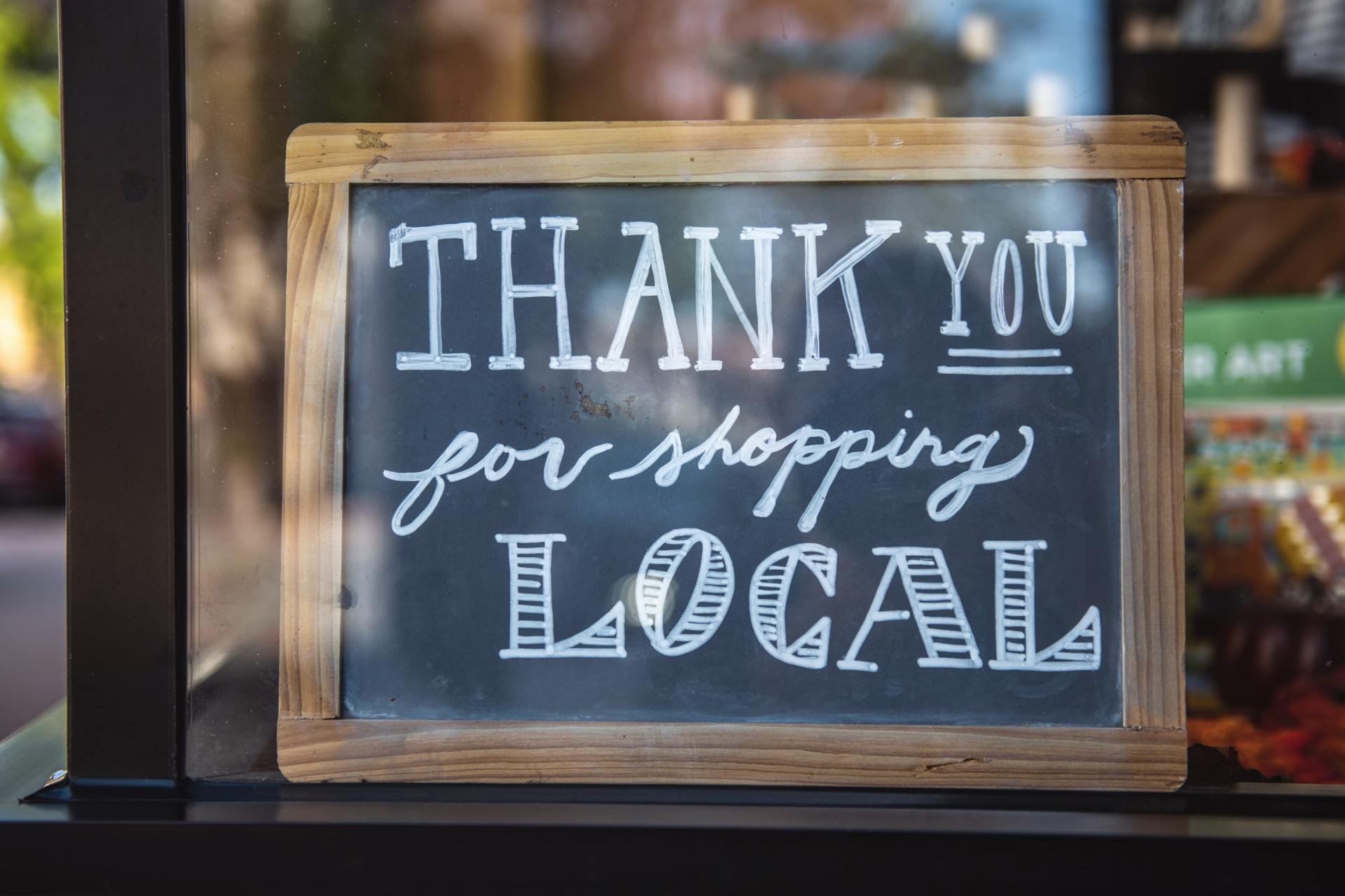A chalkboard sign that says `` thank you for shopping local ''