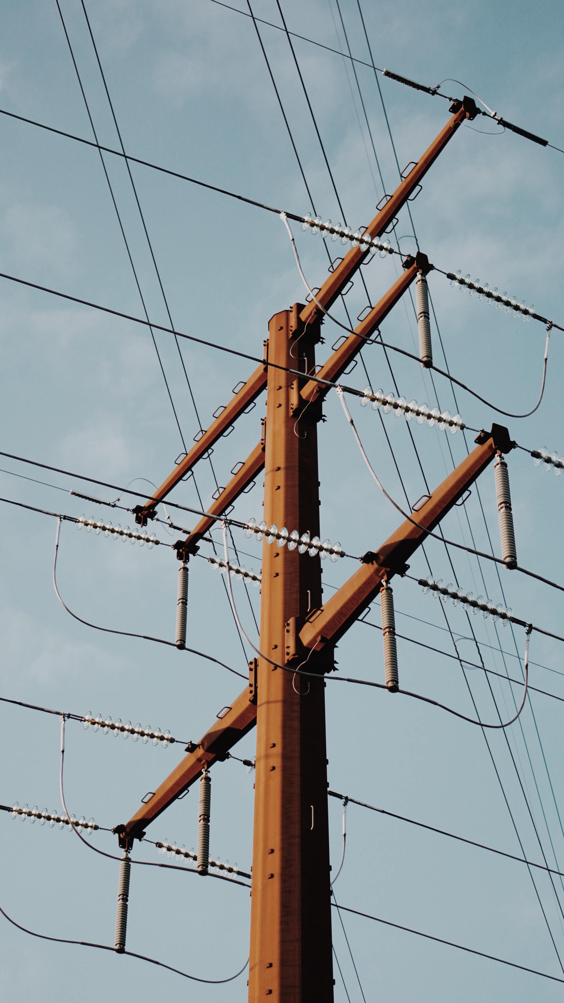 A telephone pole with barbed wire against a blue sky