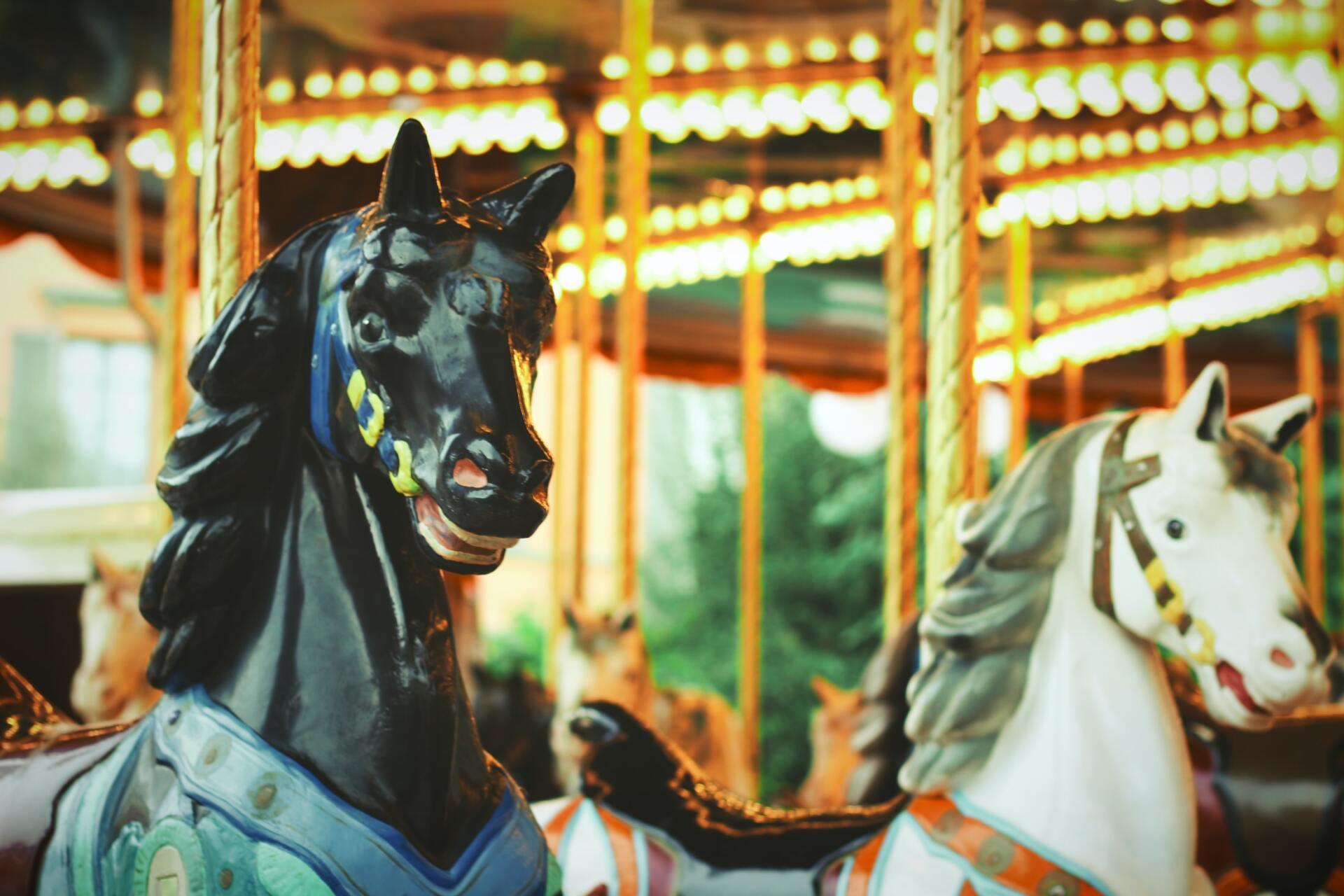 A black and white horse on a merry go round at an amusement park.