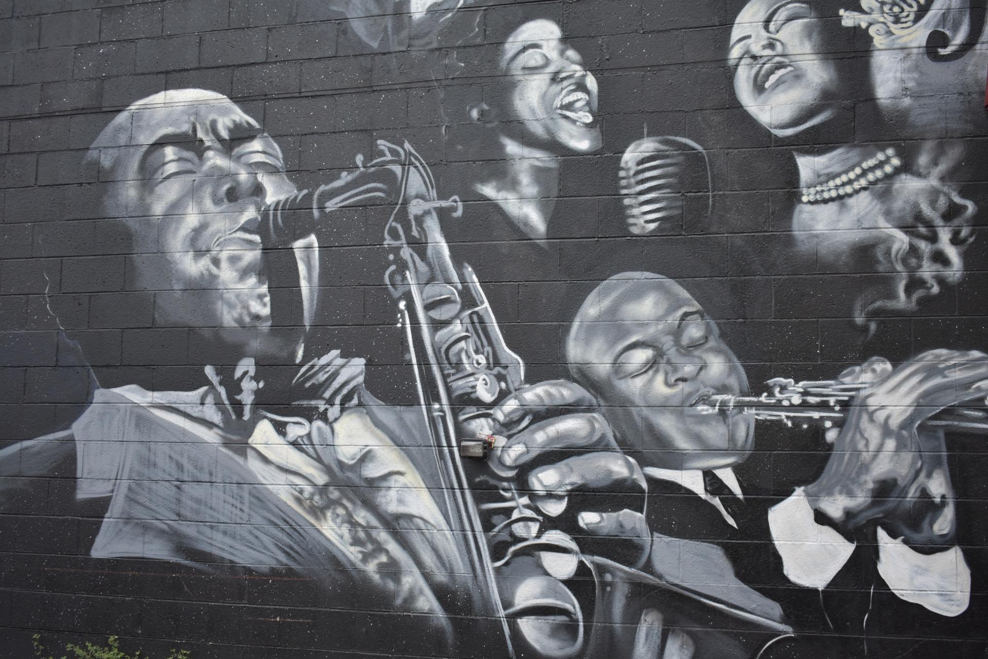 A black and white painting of a jazz band on a brick wall