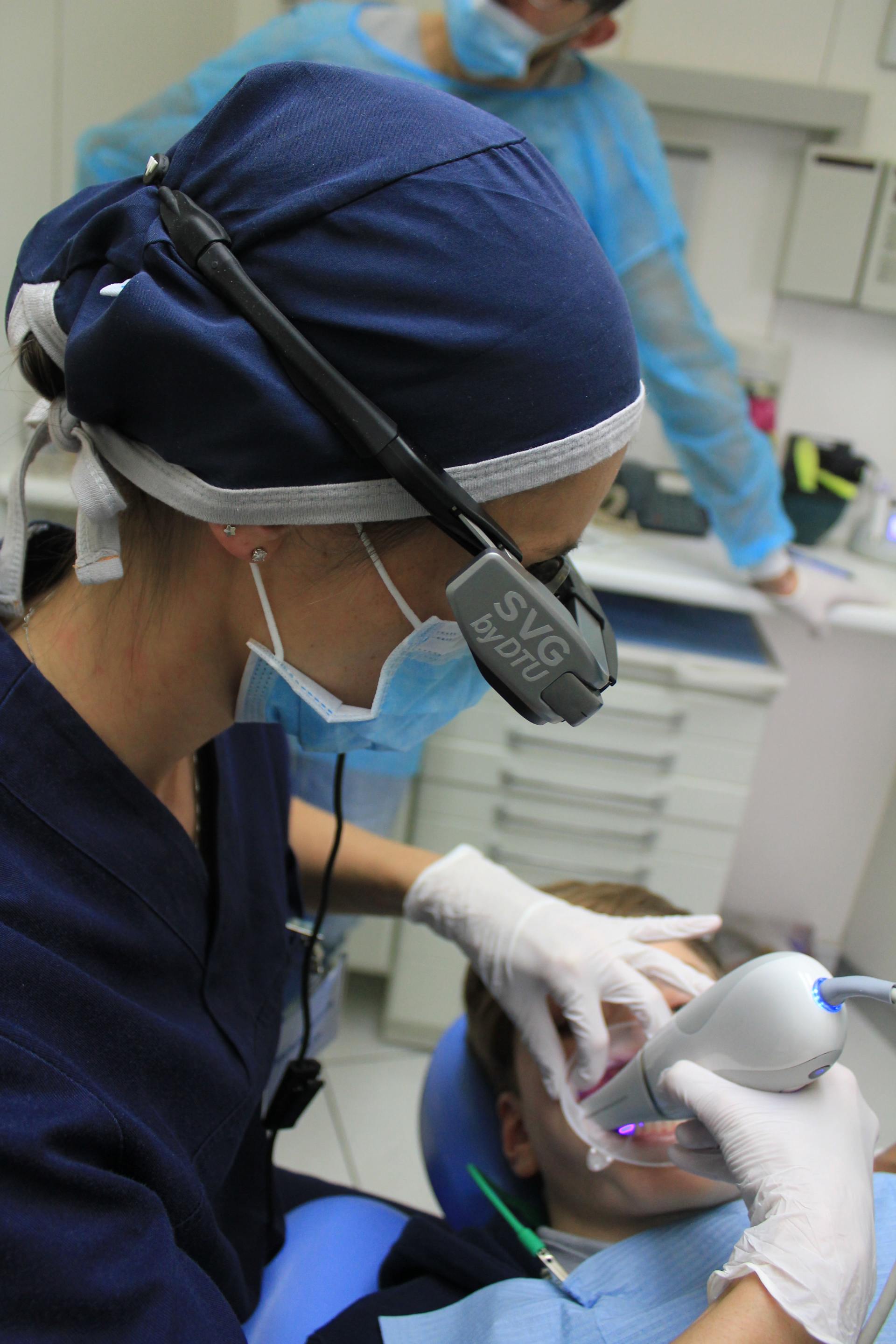 Un dentista che indossa una maschera e delle cuffie sta lavorando sui denti di un paziente