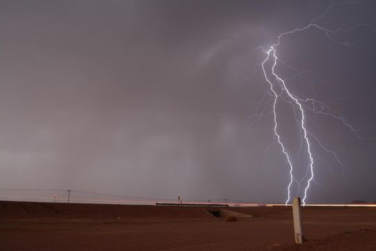 Lightning strikes over a fence post in the desert