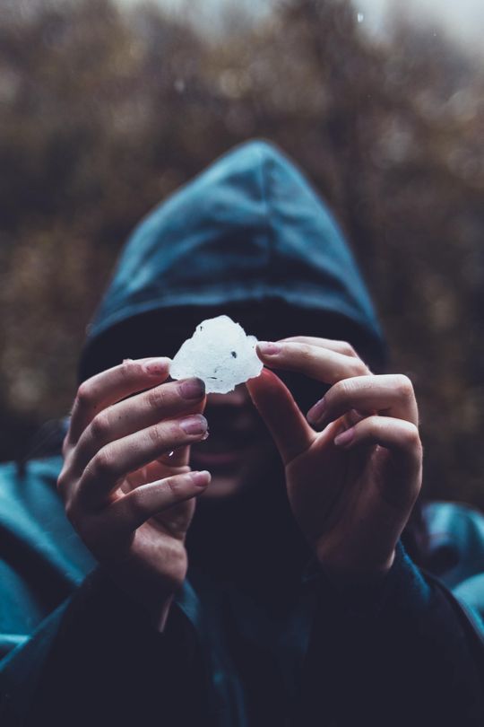 A person holding a piece of snow in front of their face