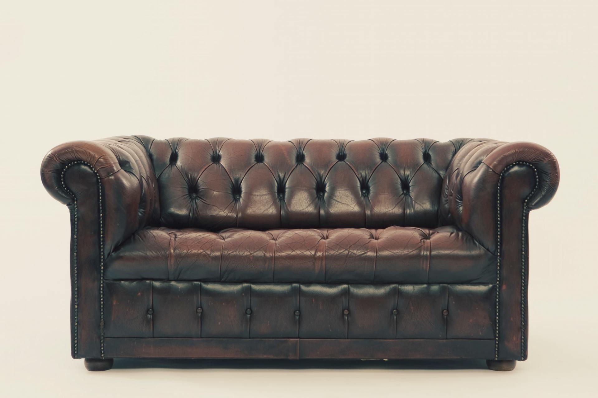 A brown leather couch is sitting on a white surface.