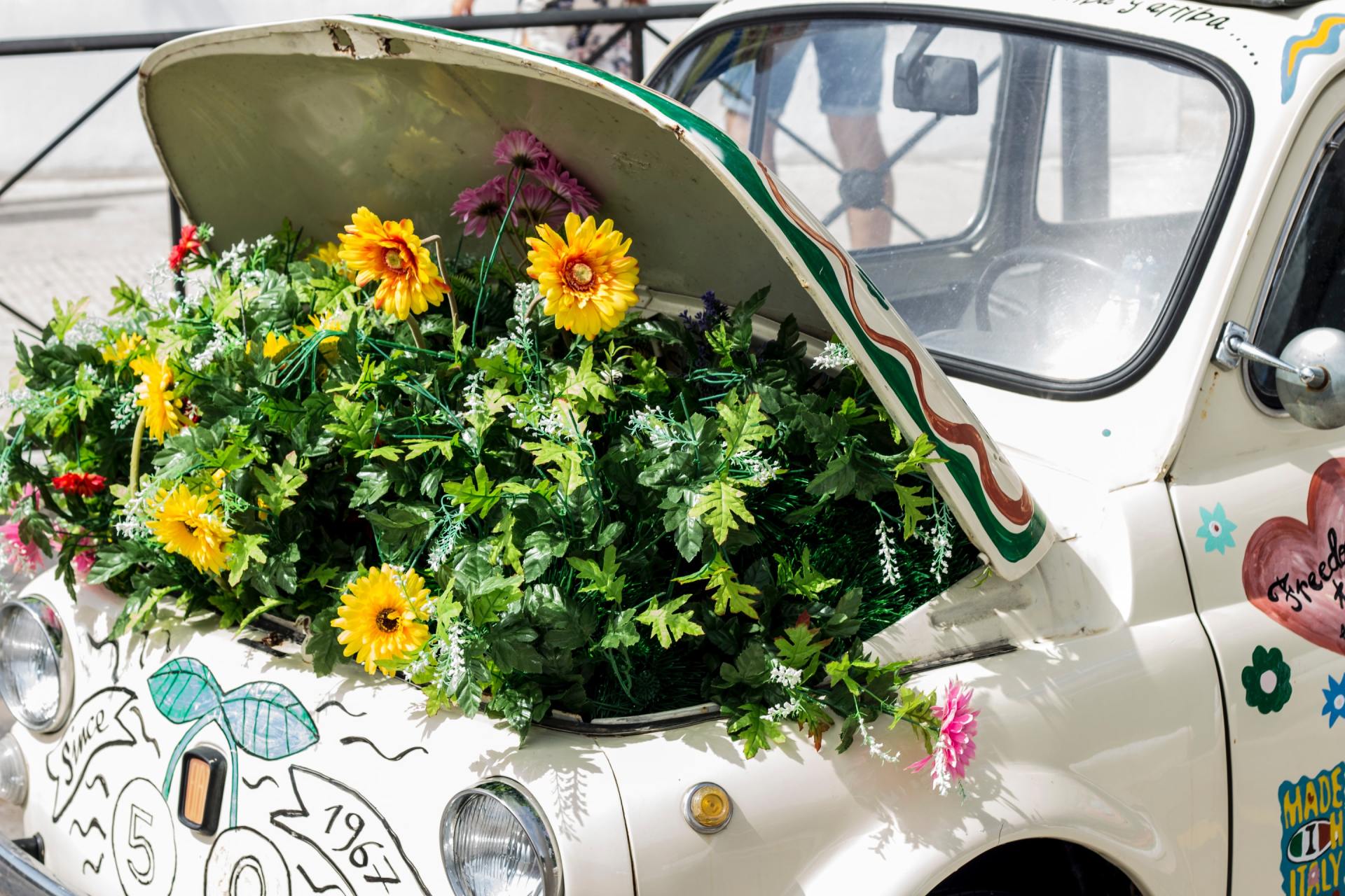 Een witte auto met de motorkap open en bloemen erop