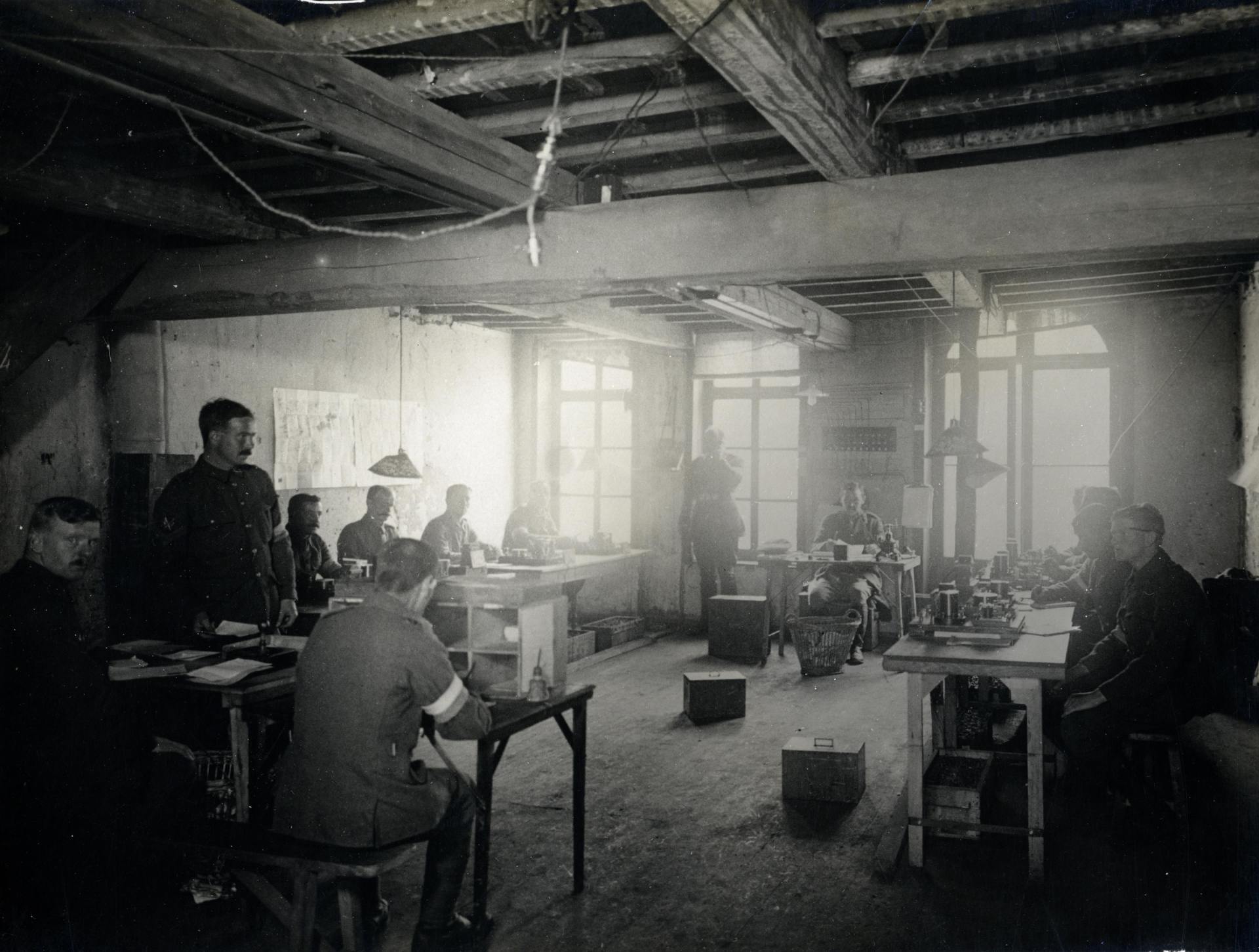 A black and white photo of a group of people sitting at tables in a room.