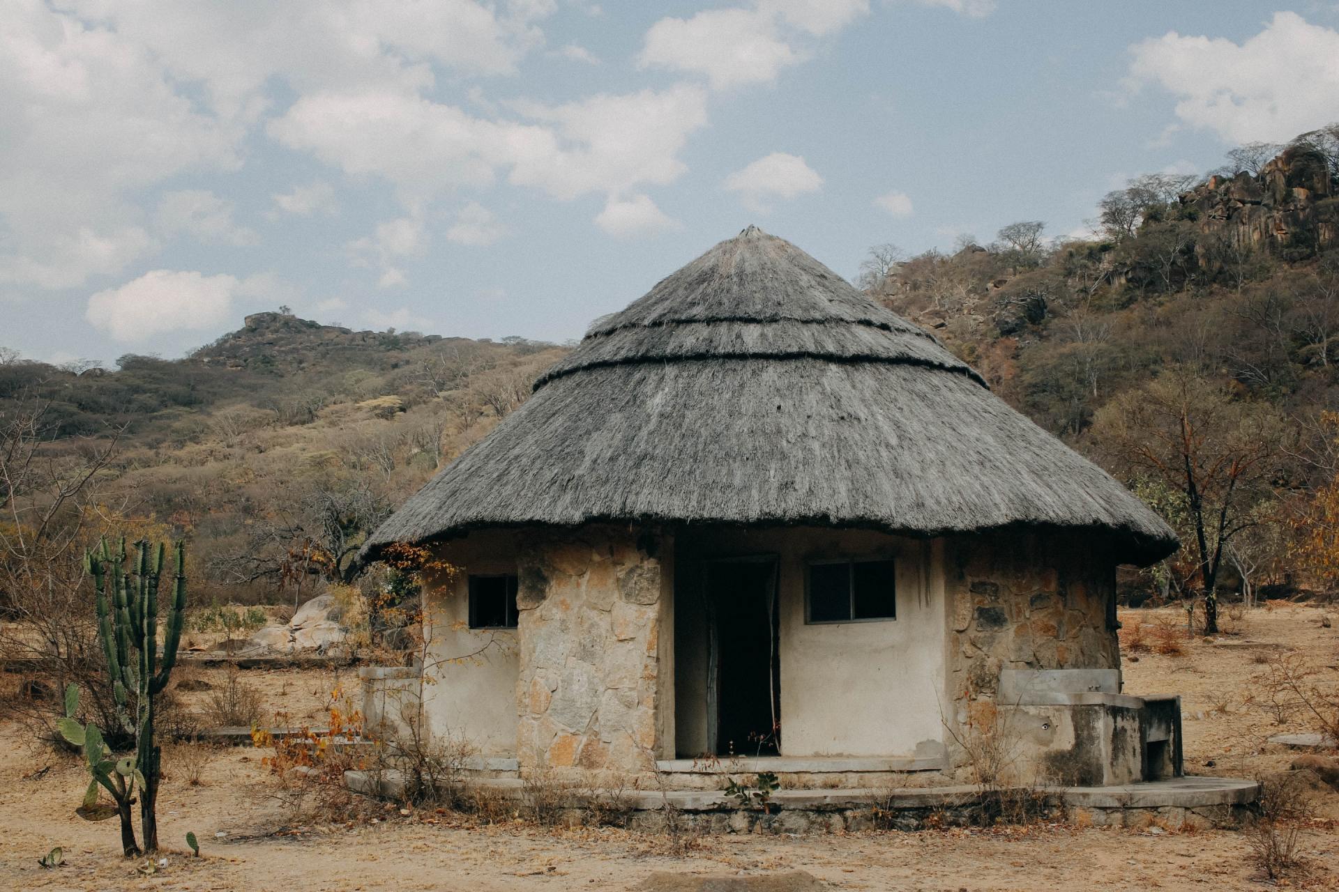 A small hut with a thatched roof in the middle of a desert.