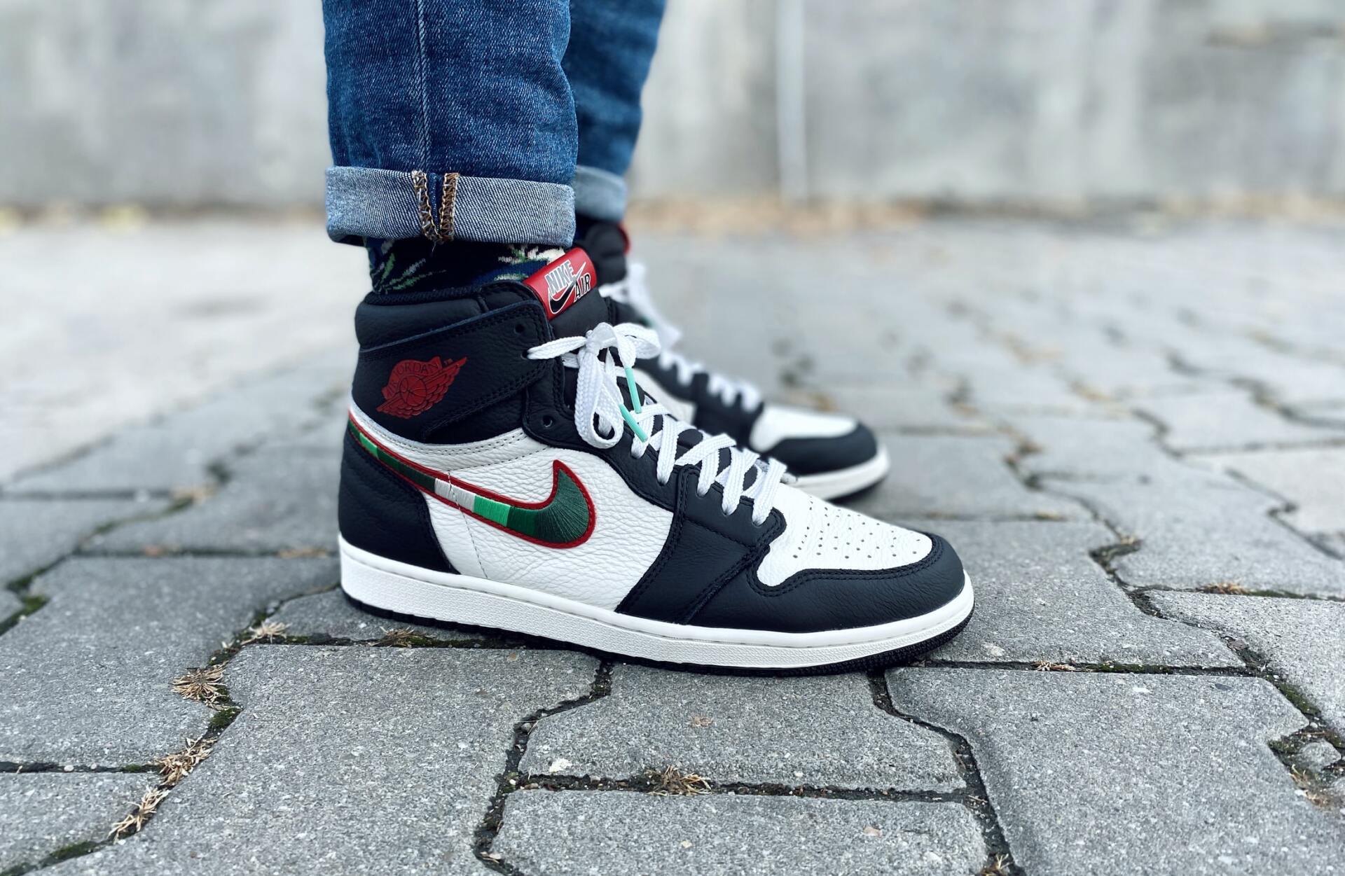 A person is wearing a pair of black and white nike air jordan 1 high sneakers.
