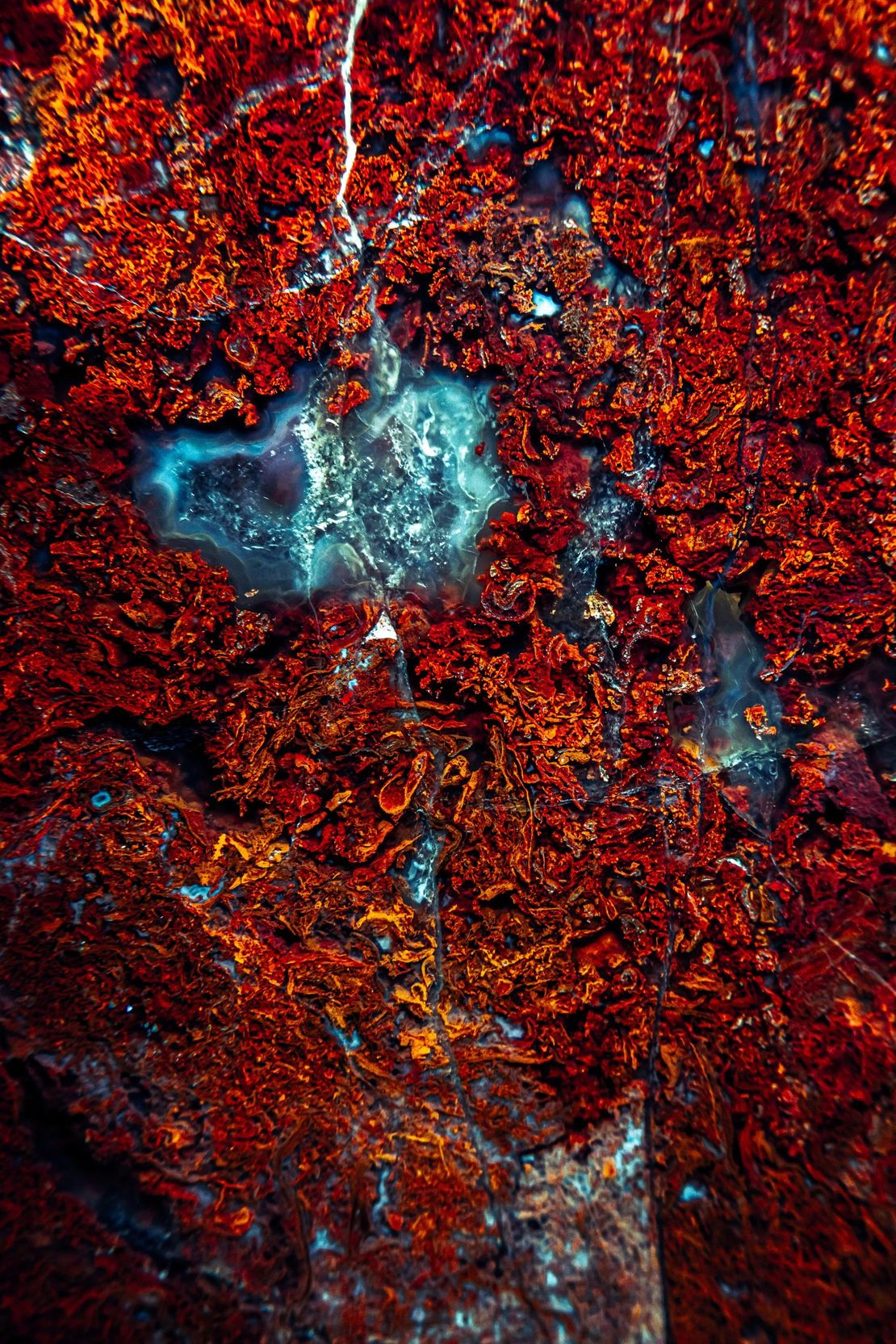 A close up of a red rock with a blue glow in the dark.