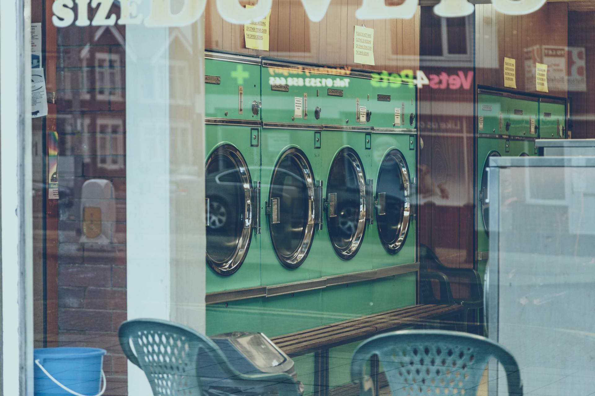 A laundromat with a lot of washing machines and chairs.
