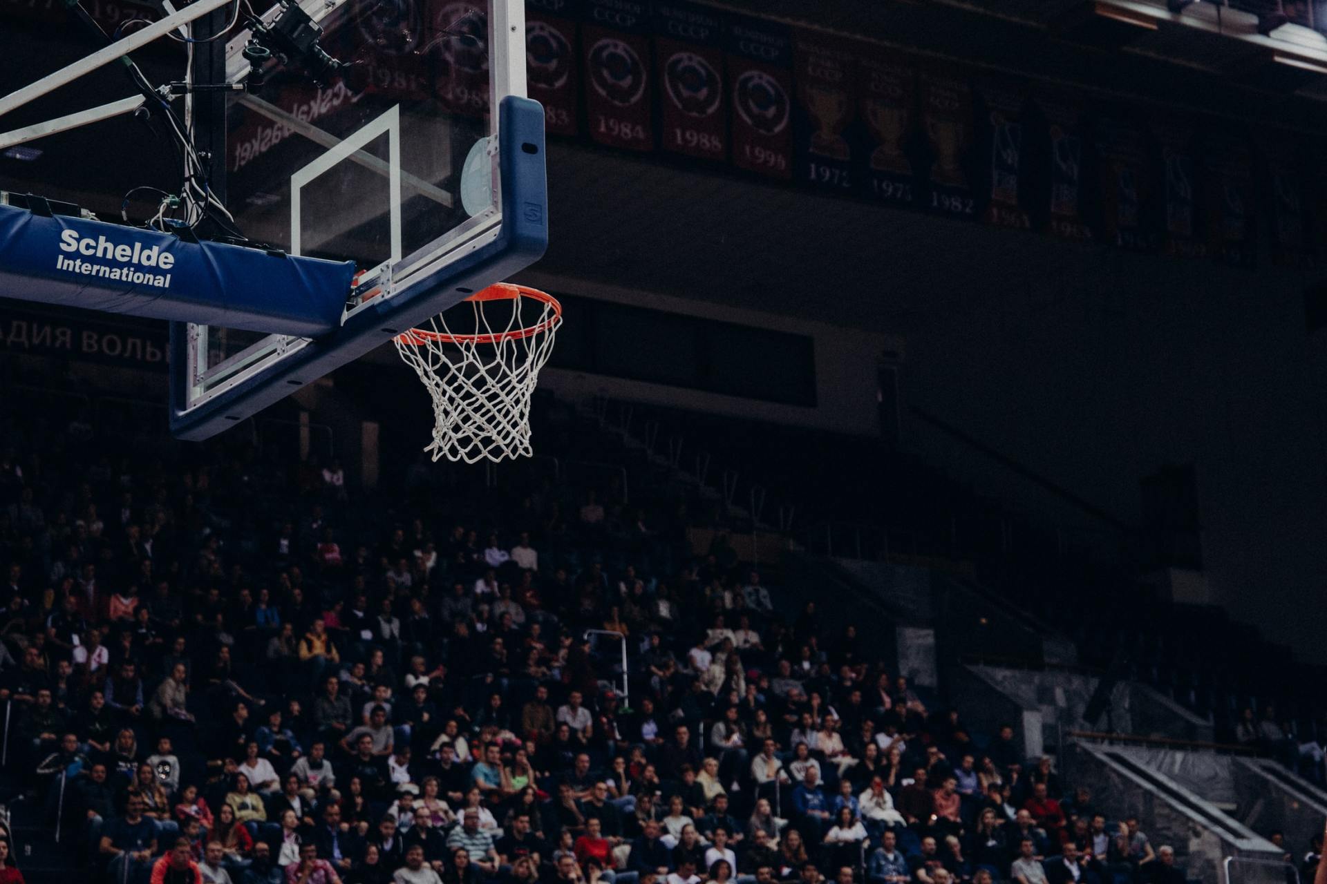 A crowd of people are watching a basketball game in a stadium.