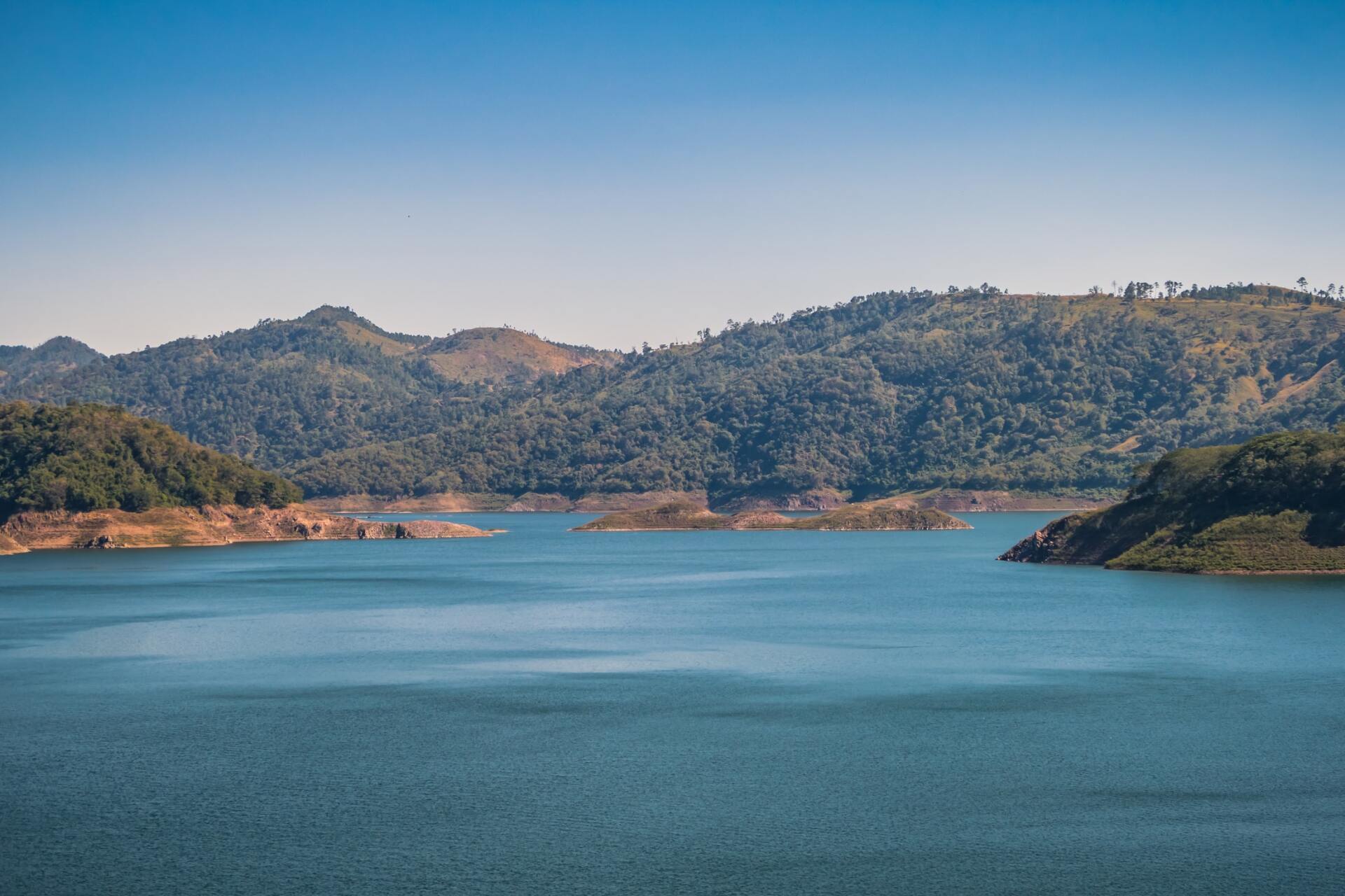 A large body of water surrounded by mountains and trees.