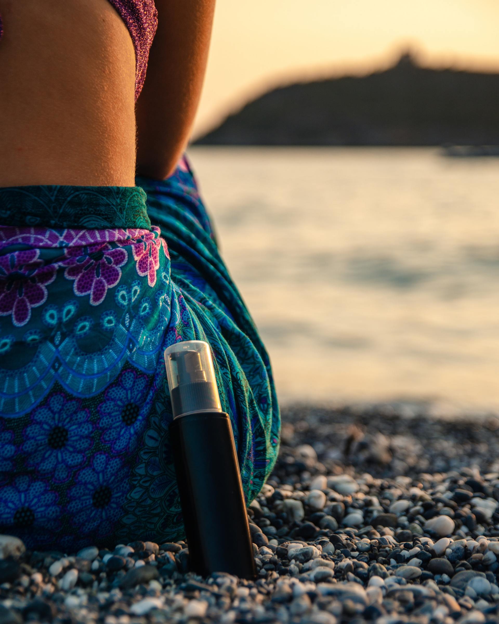 Femme assise sur la plage avec une huile de massage