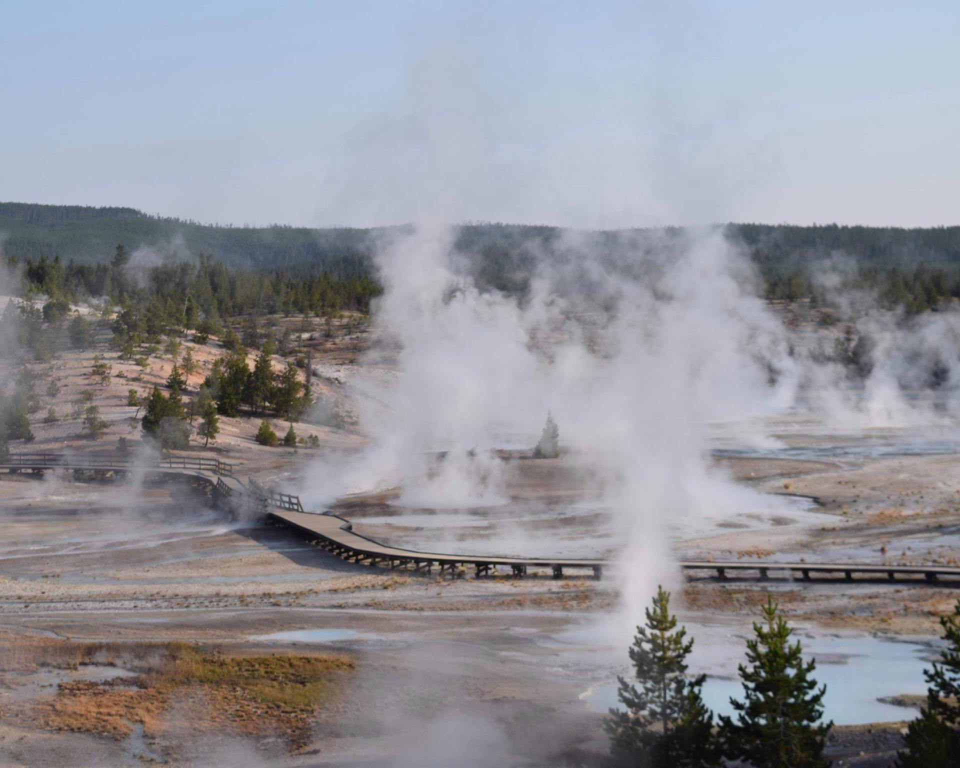 There is a bridge in the middle of a field with steam coming out of it.
