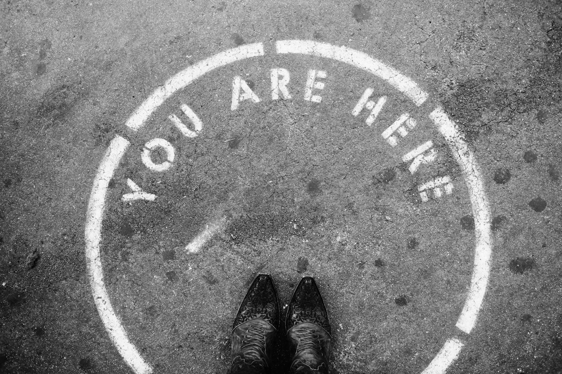 a person is standing in a circle with the words `` you are here '' painted on the ground .