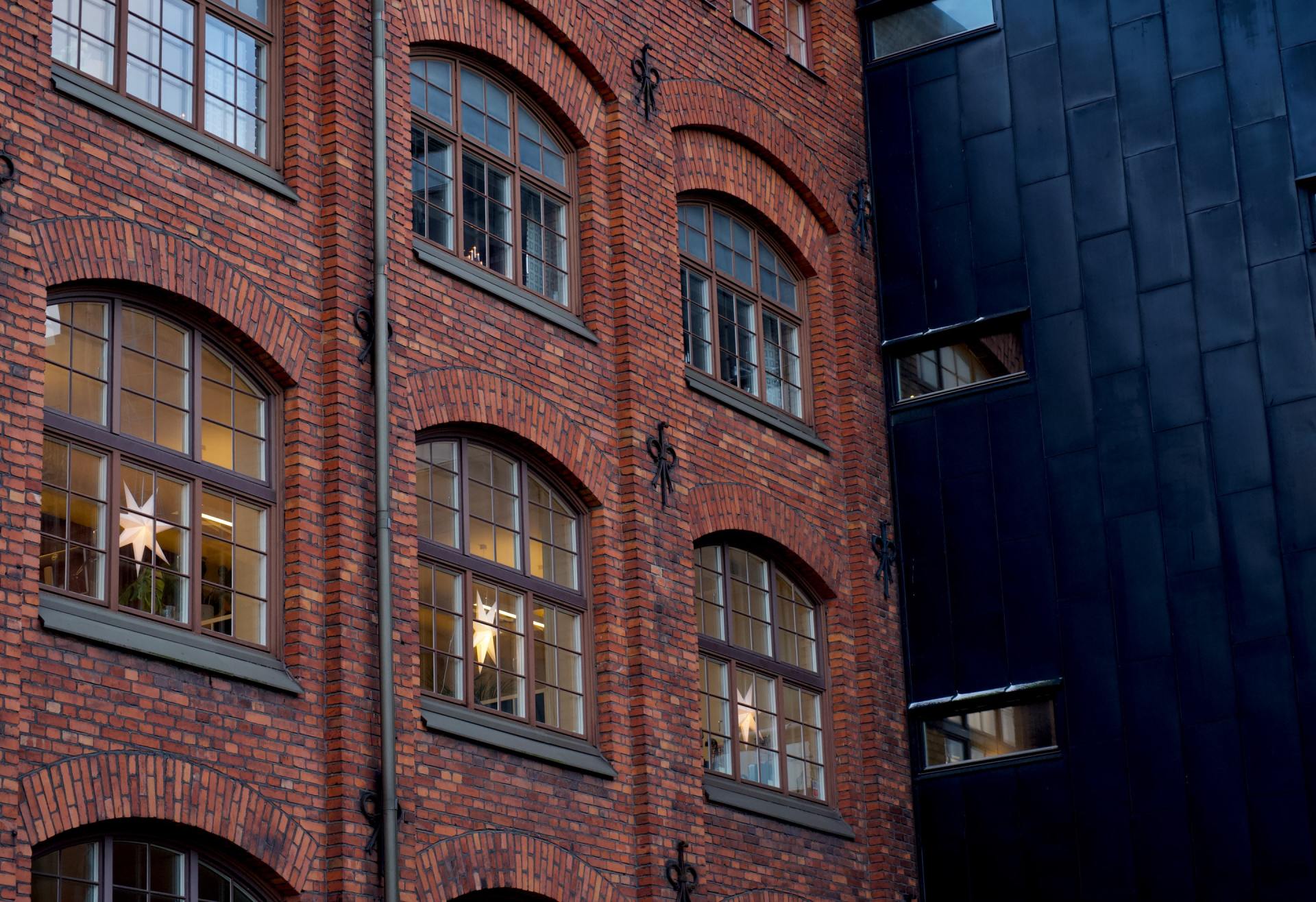 A brick building with a lot of windows and a black building in the background.