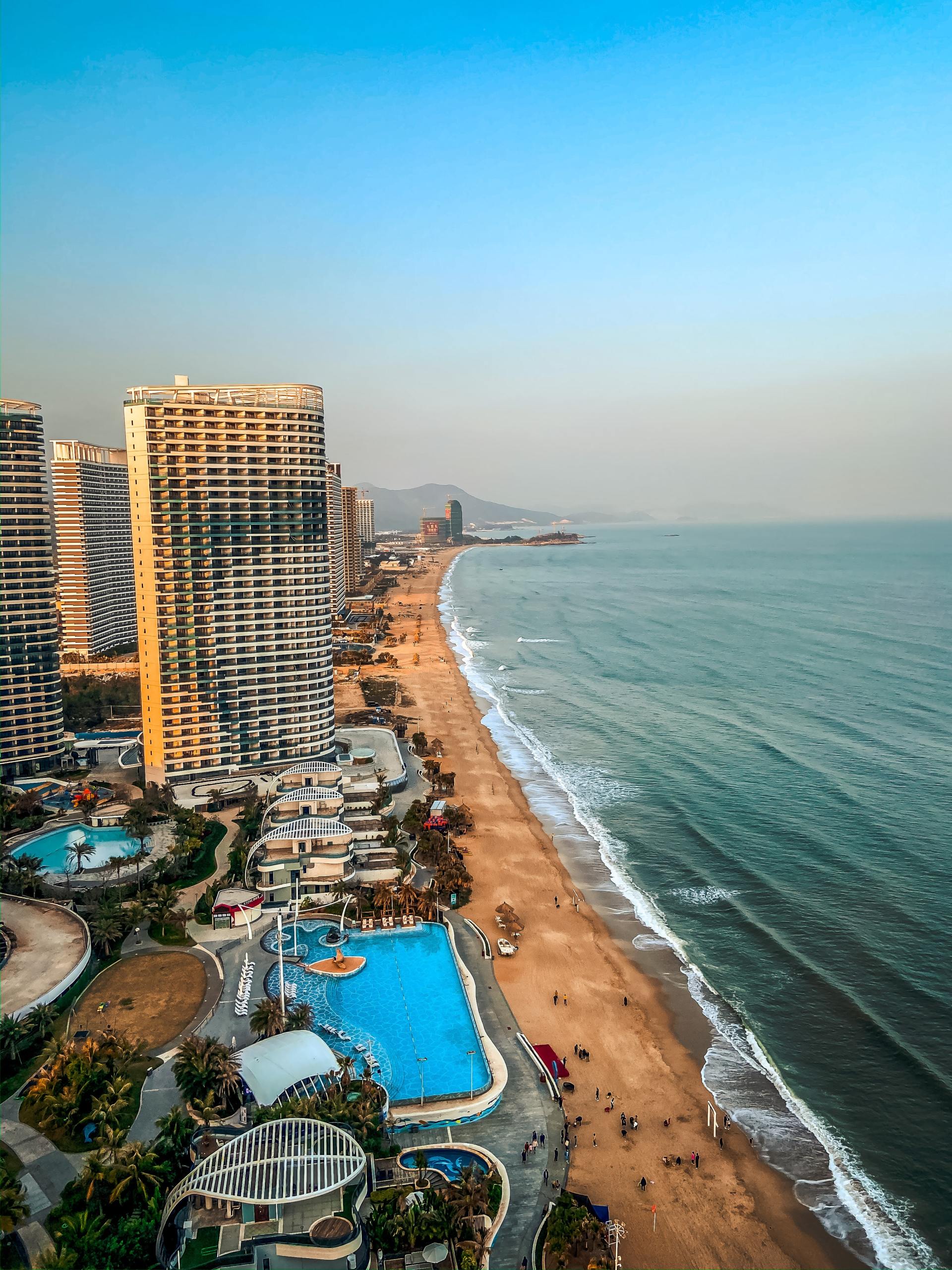 An aerial view of a beach with buildings and a pool.