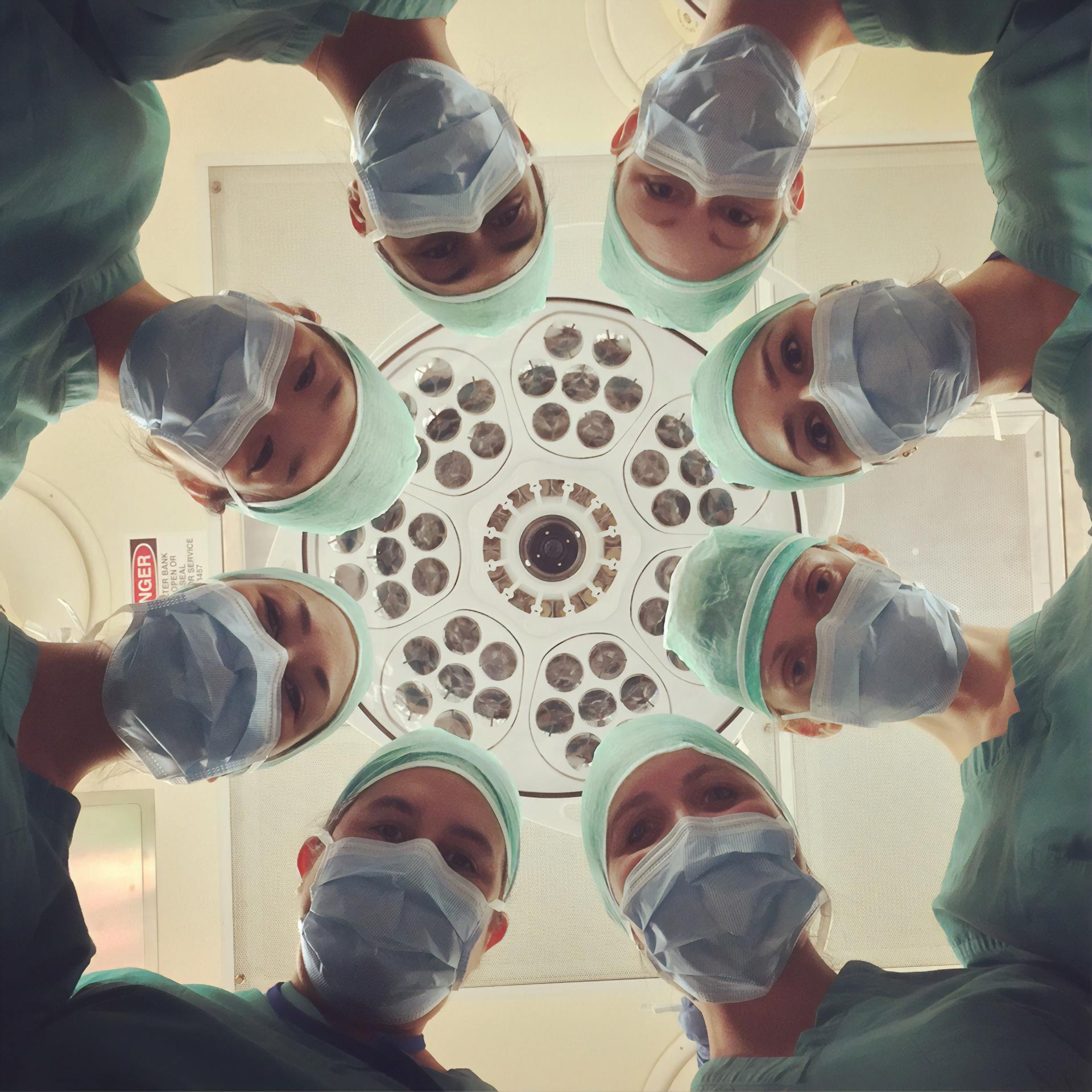 group of doctors with face masks looking down at patient on operating table