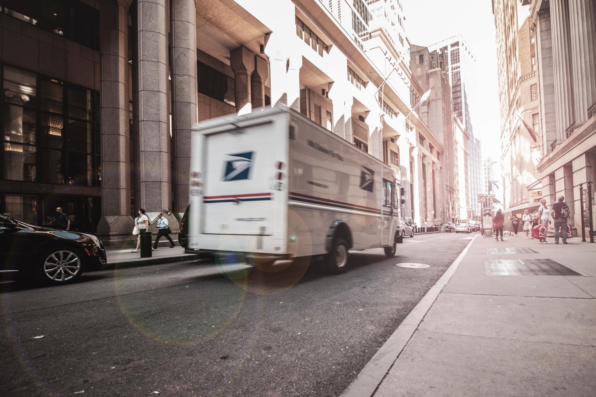 A mail truck is driving down a city street.