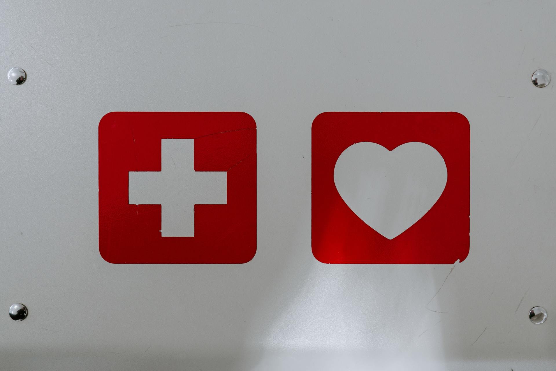 un cartello bianco con una croce rossa e un cuore bianco