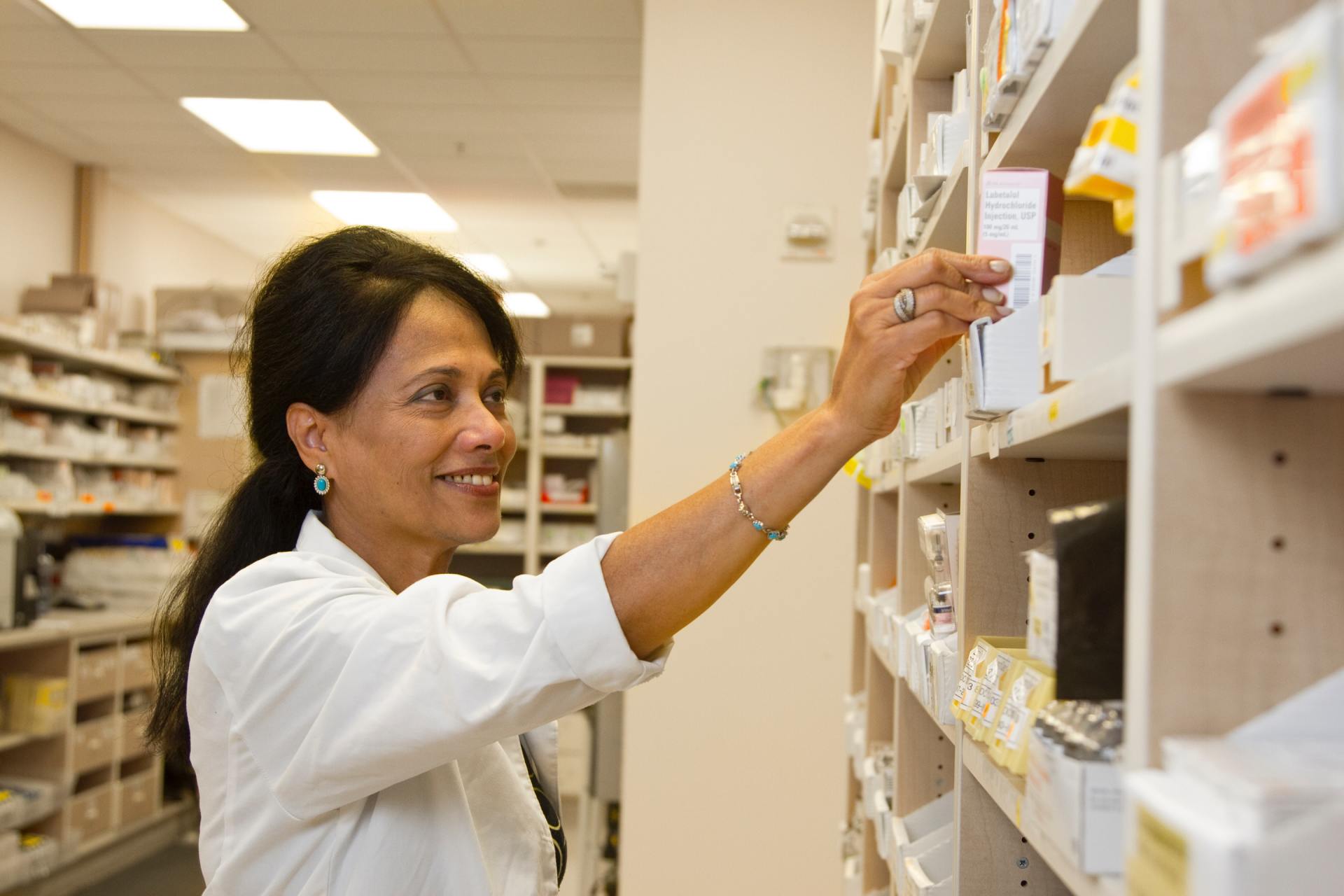 una donna in una farmacia seleziona un medicinale da uno scaffale