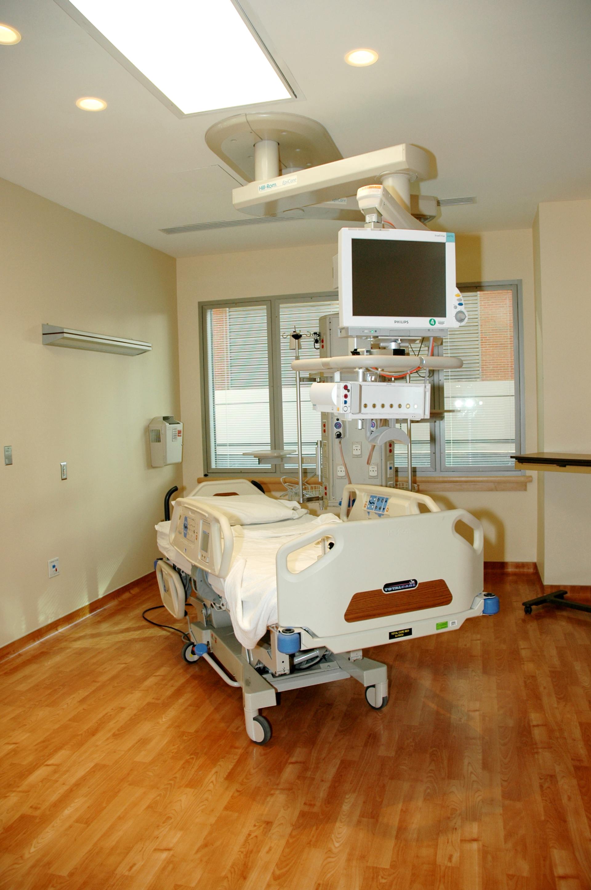 A hospital bed with a monitor hanging from the ceiling