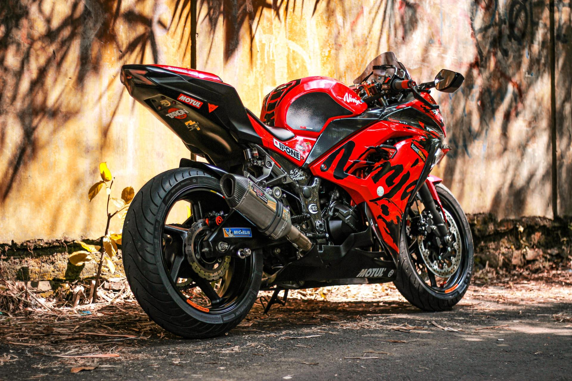 A red and black motorcycle is parked on the side of the road.