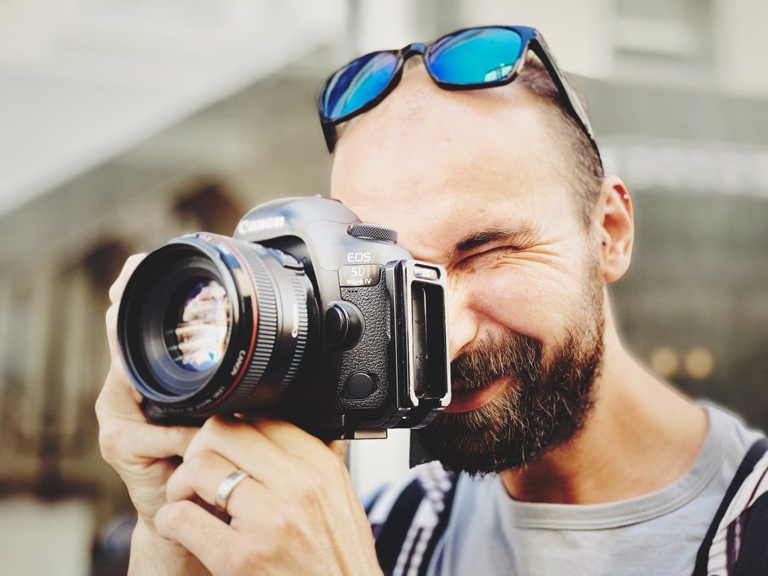 A man with a beard is taking a picture with a camera.