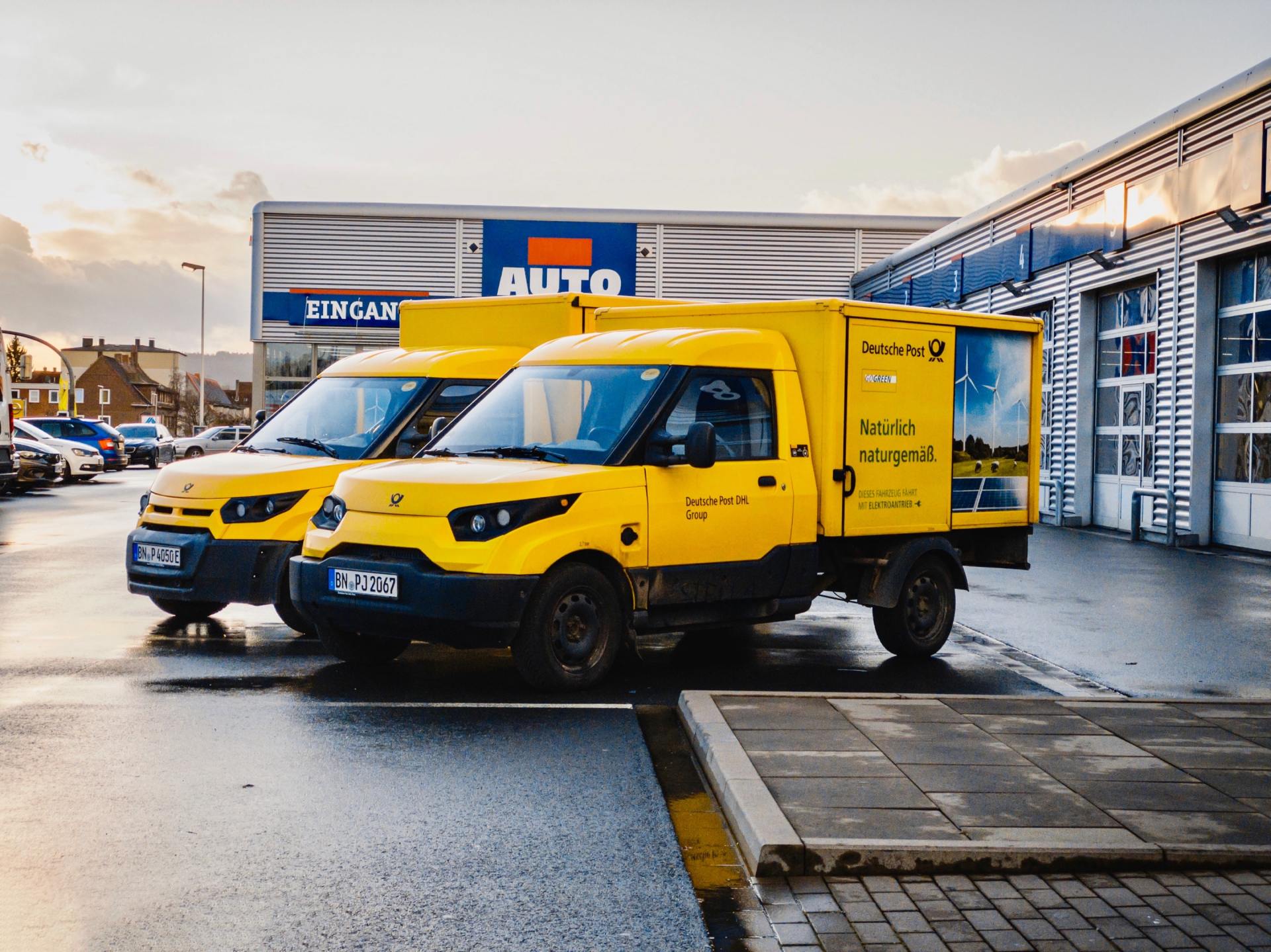 Two yellow vans are parked in a parking lot in front of a building.
