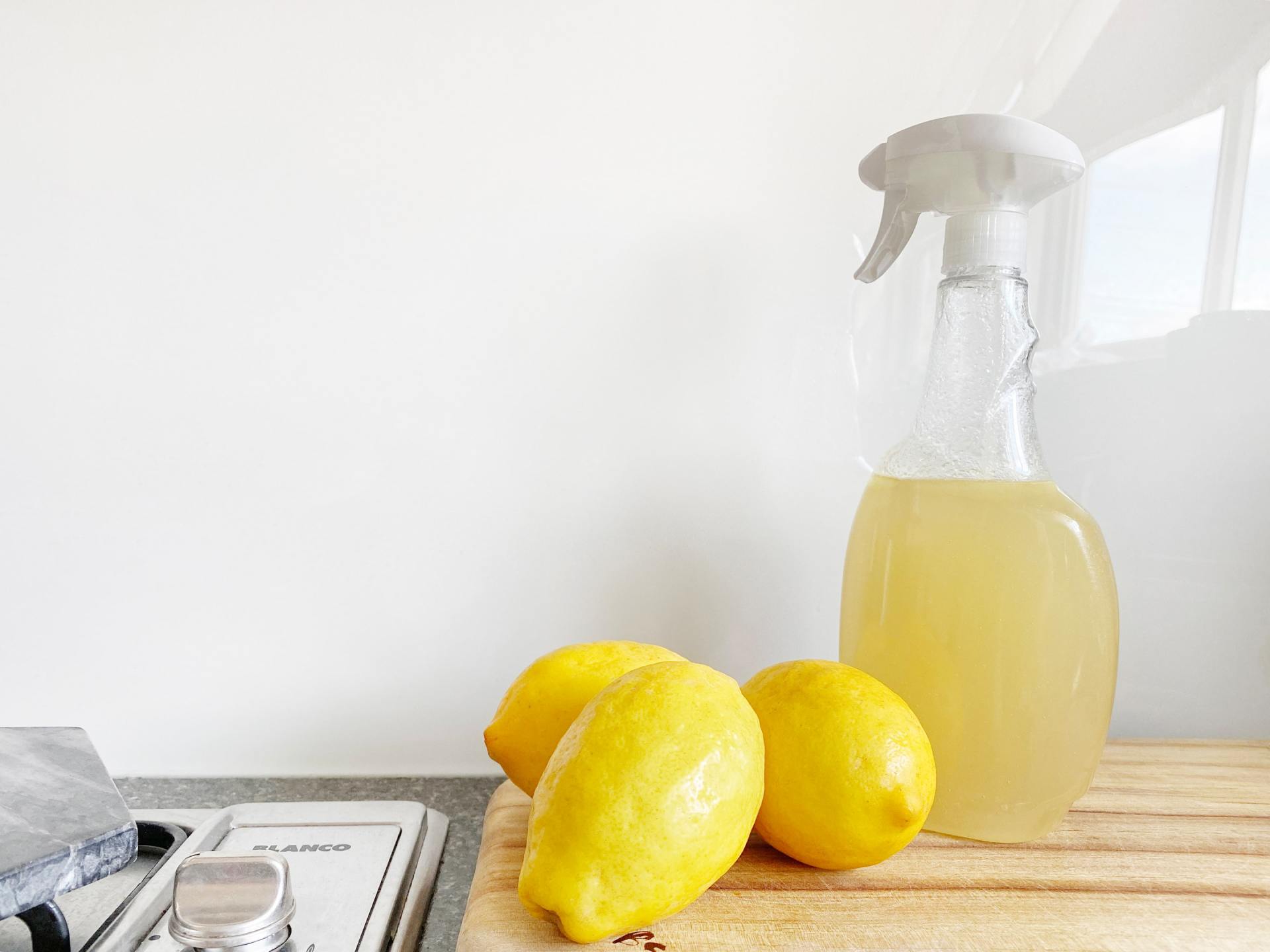 Cleaning chemicals in a spray bottle next to lemons
