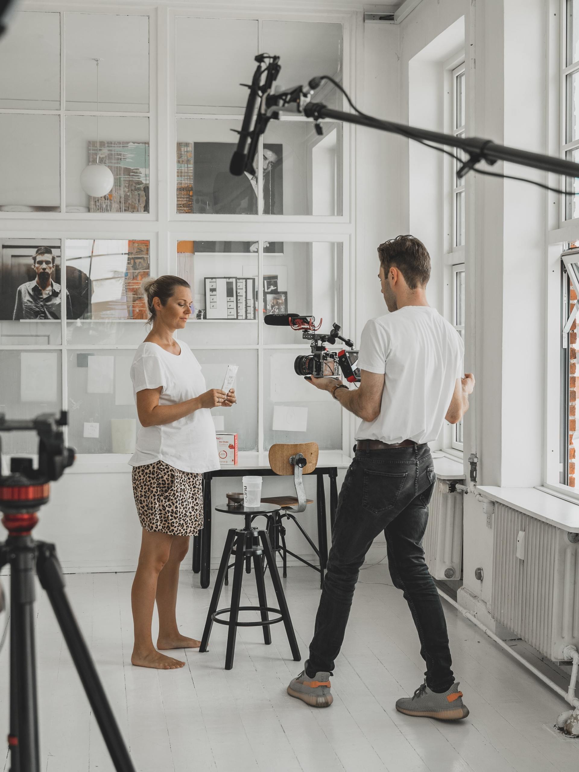 A man is holding a camera and talking to a woman in a room.