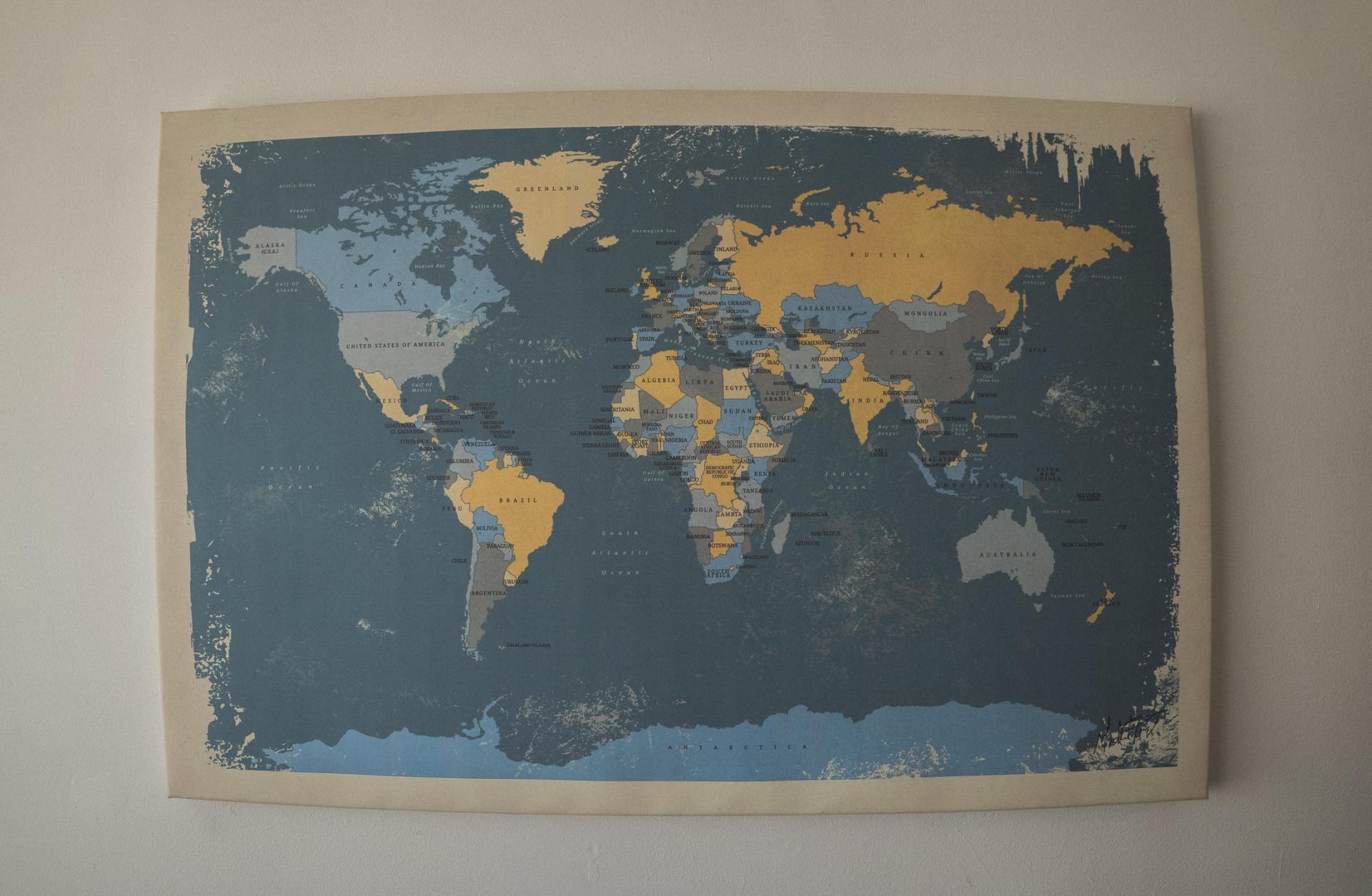 A map of the world is hanging on a white wall