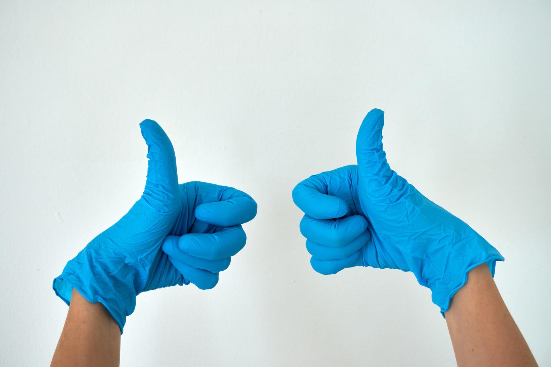 Image of two thumbs up wearing gloves during COVID-19