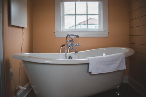 clawfoot bathtub with a peach color painted wall