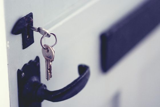 in this image a set of keys dangle from a lock on a smart white door with black hardware