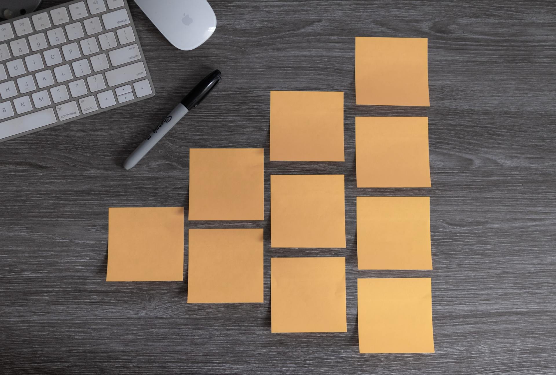 A bunch of sticky notes on a wooden table next to a keyboard and mouse.